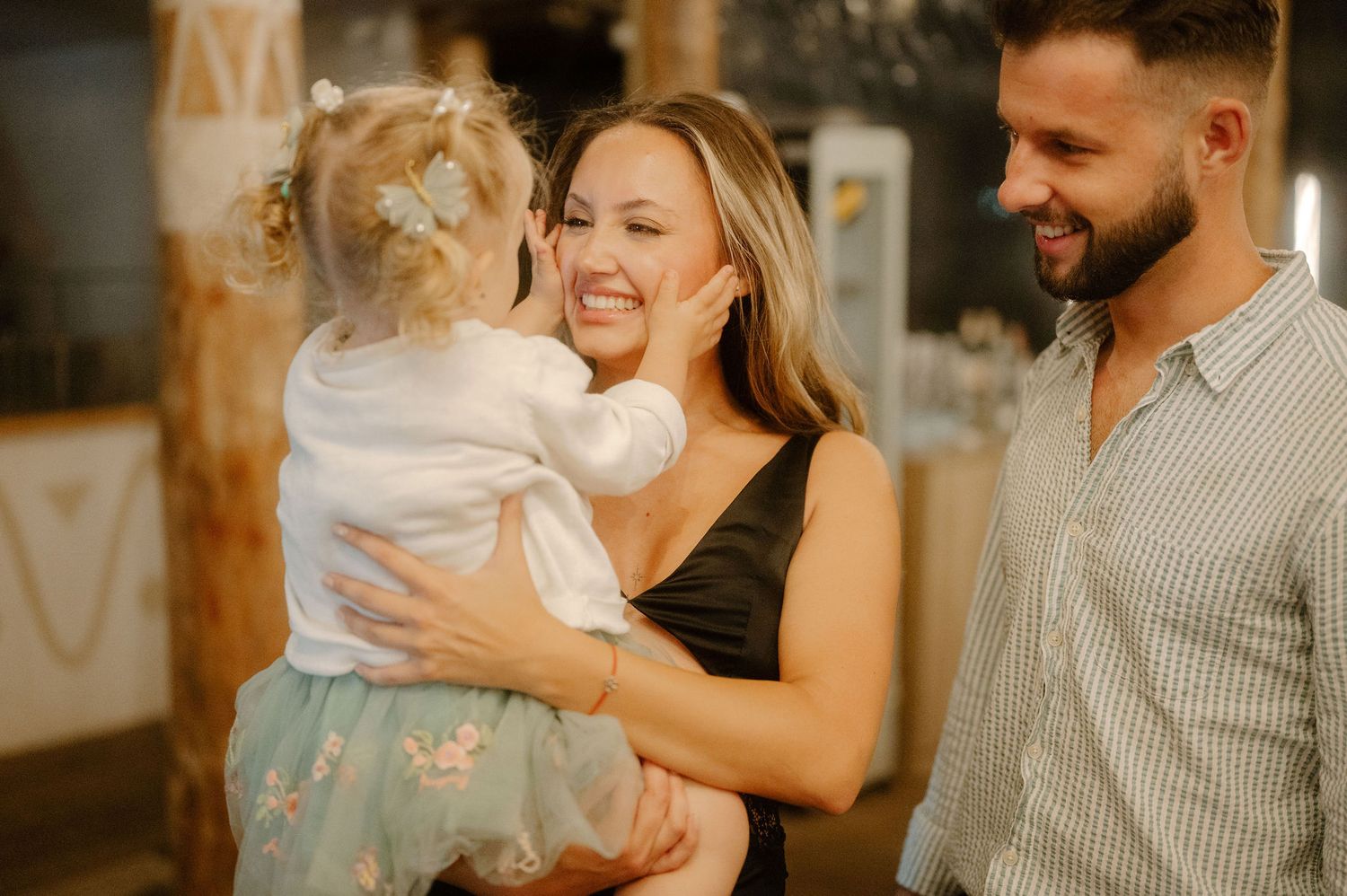 A joyful family moment captured in warm lighting with a small child wearing a tulle skirt.