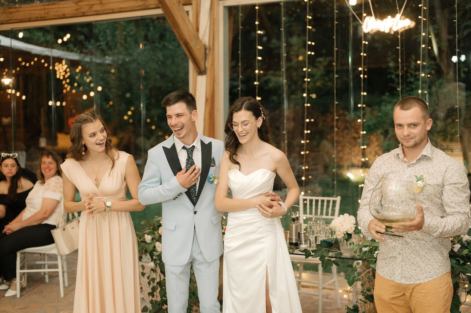 Guests enjoy festivities at a romantic wedding reception venue decorated with warm lighting and greenery.