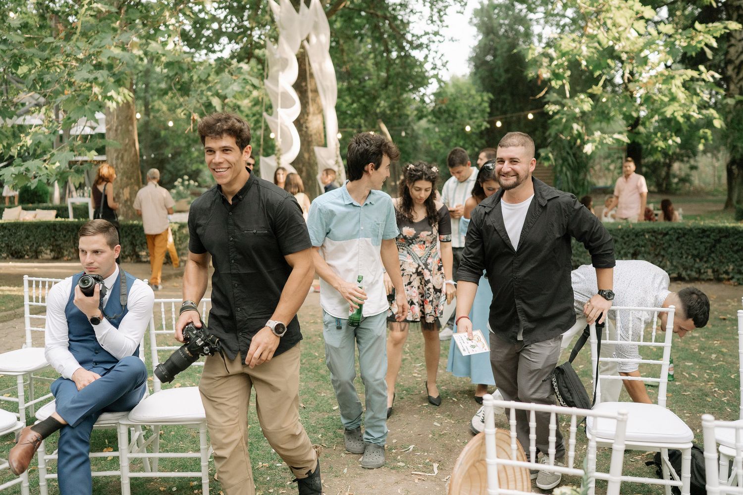 Wedding guests gather outdoors in a garden setting during a casual summer celebration.