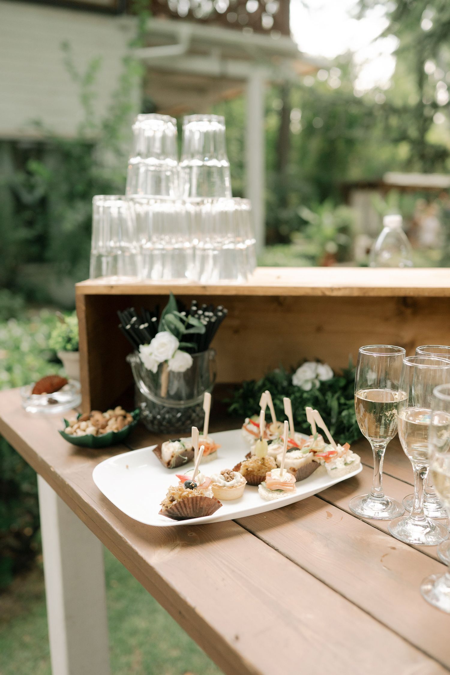 Elegant outdoor dining setup with wine glasses and appetizer plates arranged on a rustic wooden table.