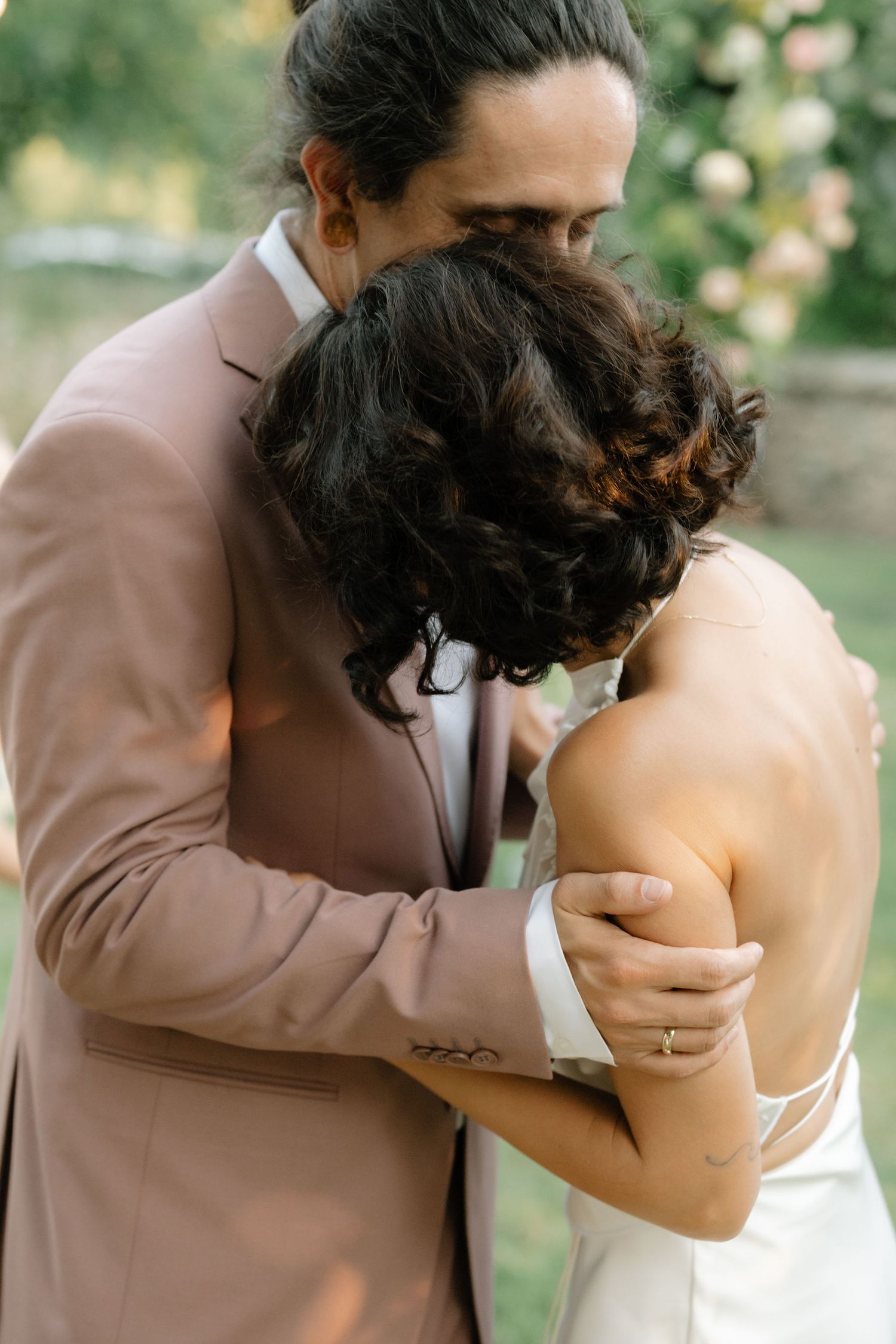 A romantic first kiss sequence between newlyweds at an outdoor wedding ceremony with soft natural lighting.