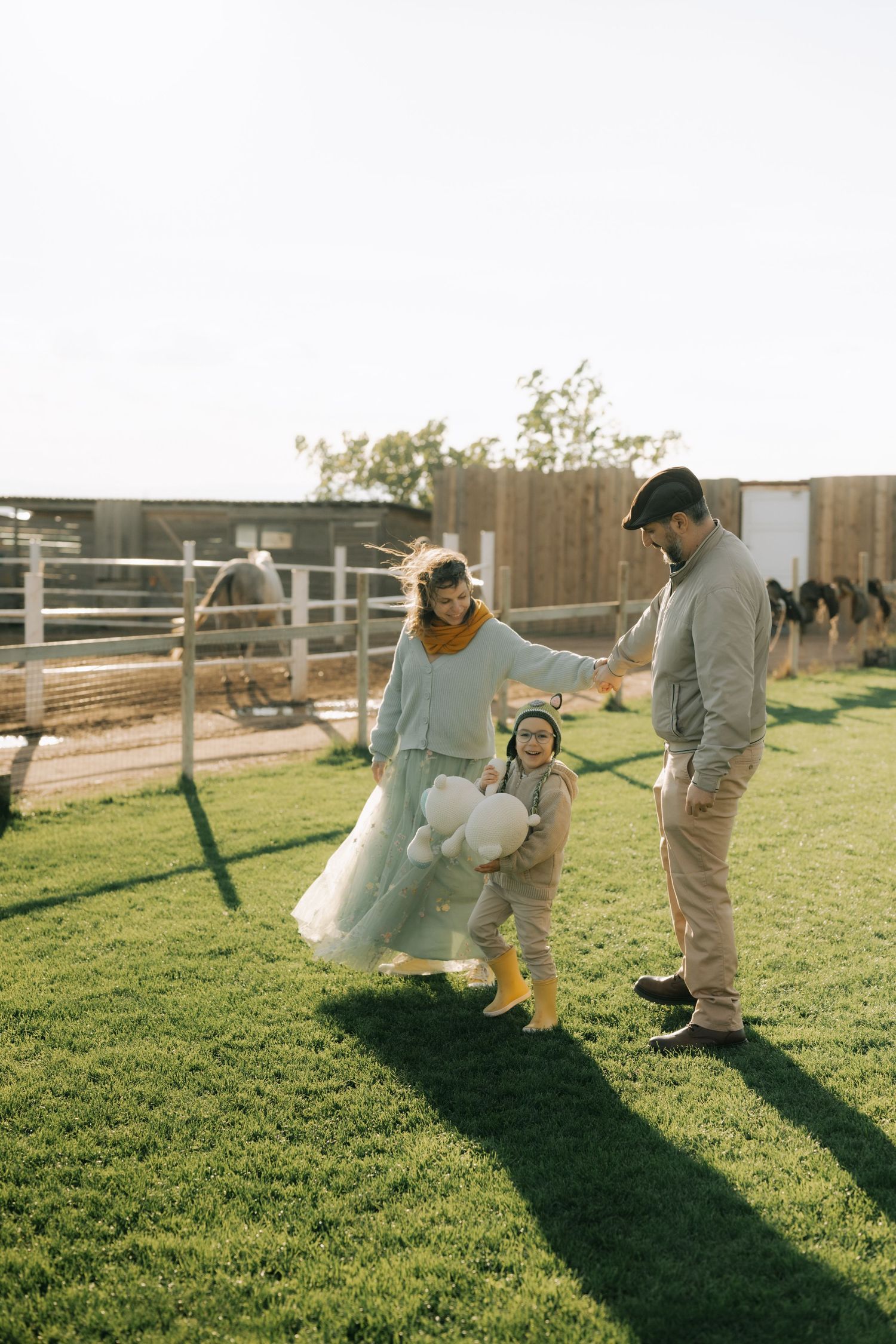 A sequence of images showing a couple playing and swinging together on a sunny day in a grassy field with wooden fences.