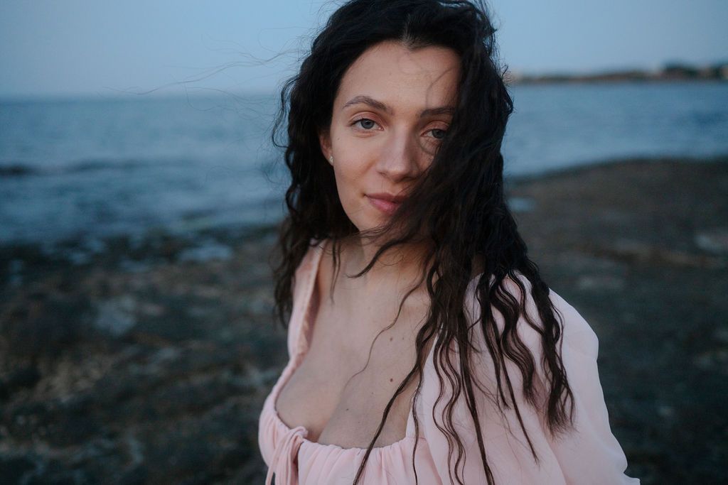Moody portrait series of someone with wet dark hair against a dramatic coastal backdrop at dusk.