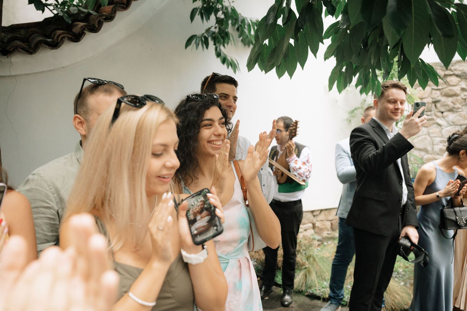 A group celebrating outdoors under green tree branches.
