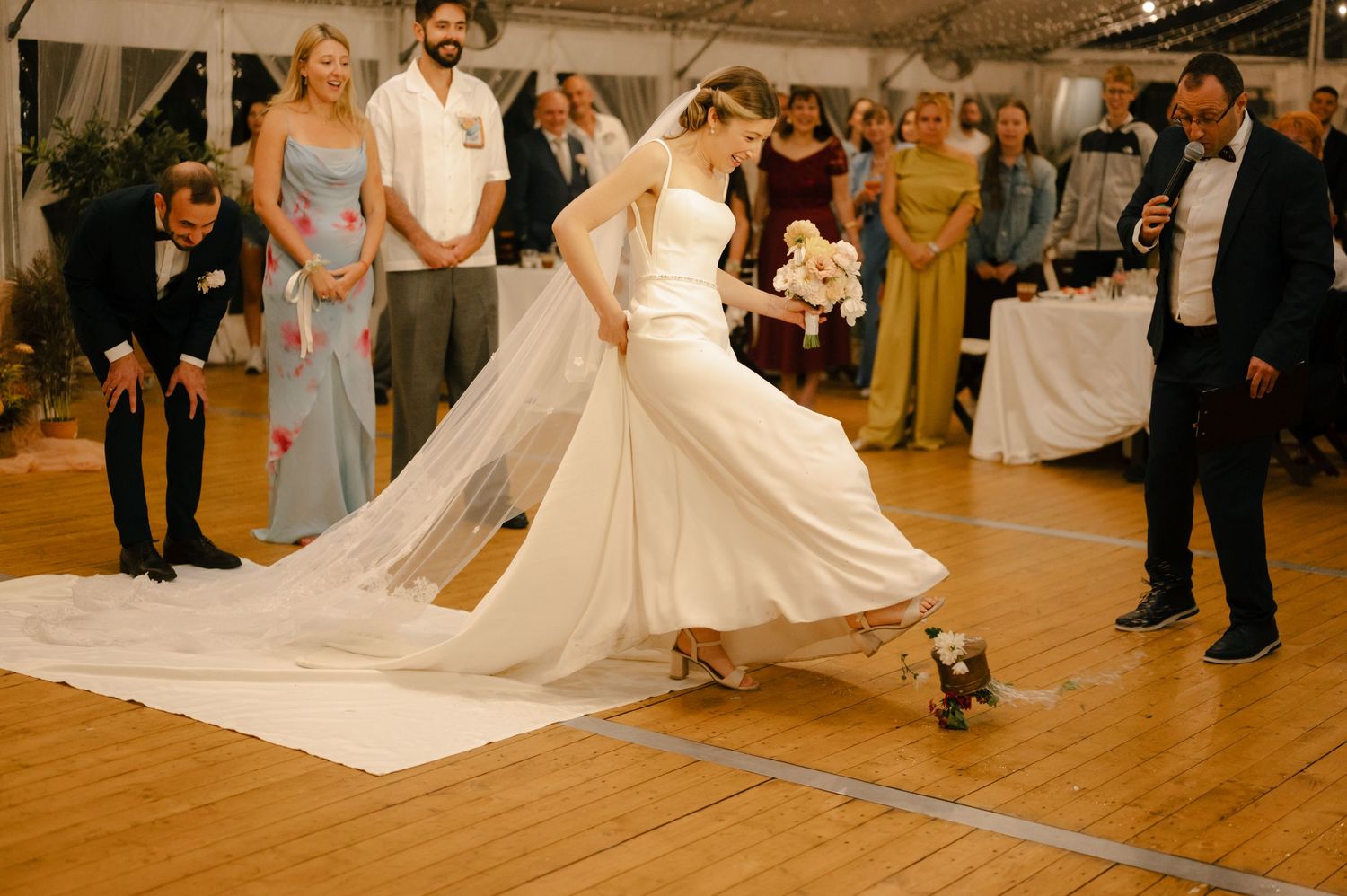 A couple performs an elegant twirling dance move on a wooden floor during a wedding reception.