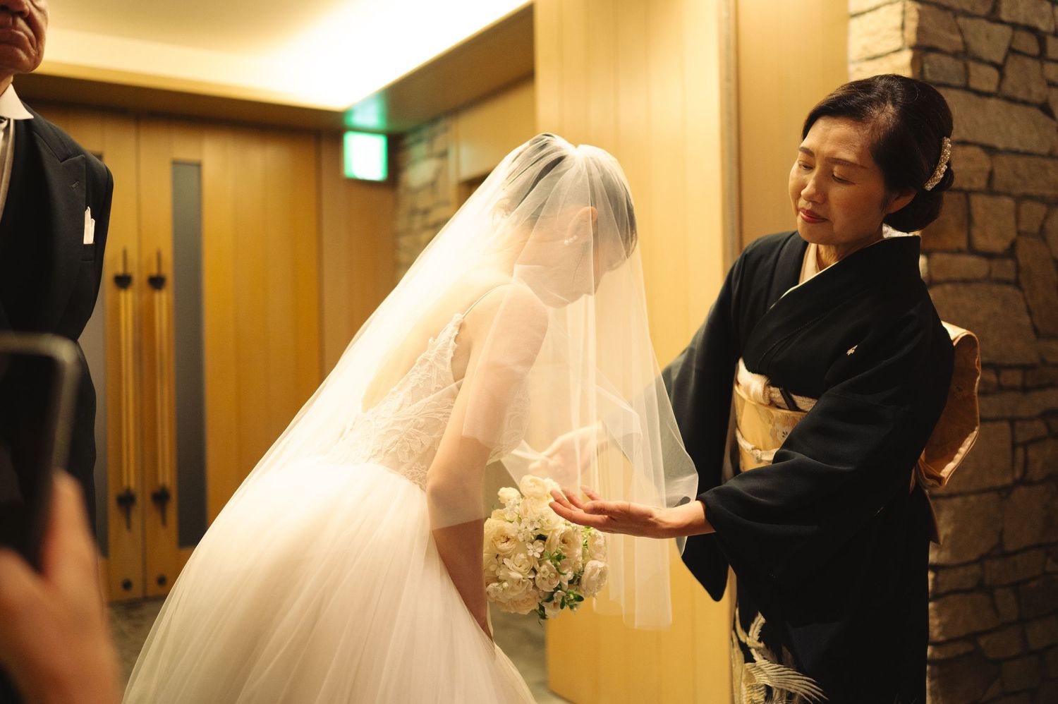 Wedding dress preparation with attendant making final adjustments to bride's flowing veil.