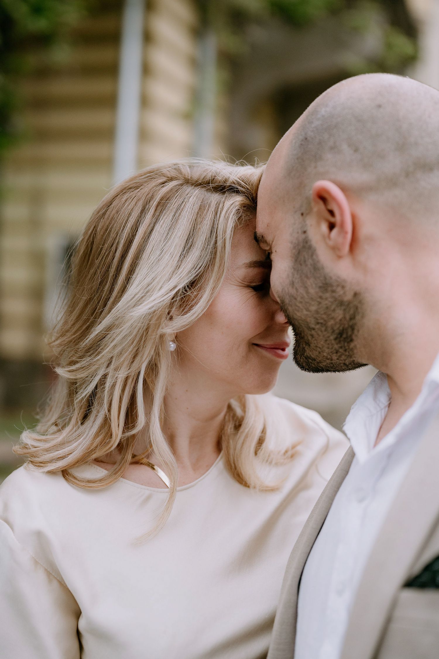Romantic couple in white and beige outfits sharing intimate moments outdoors.