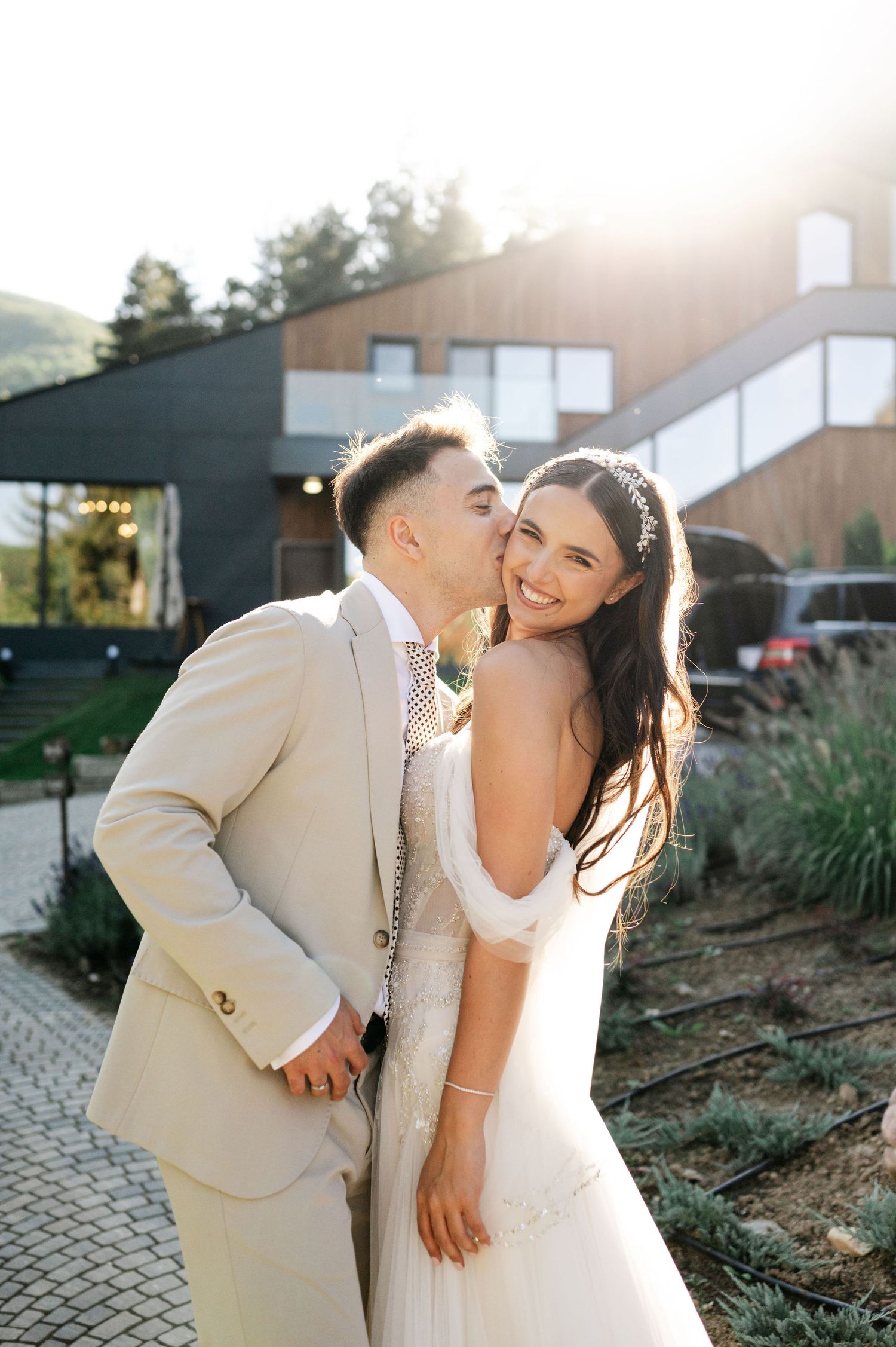 A tender moment between newlyweds captured in warm sunlight on a stone patio.