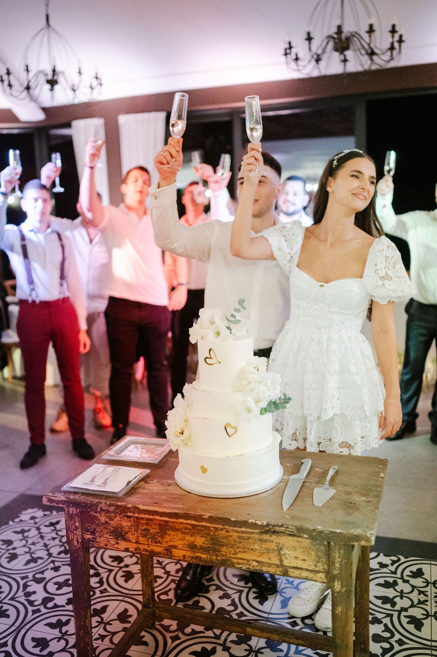 Wedding reception setup featuring white cake on rustic table with decorative floor pattern.