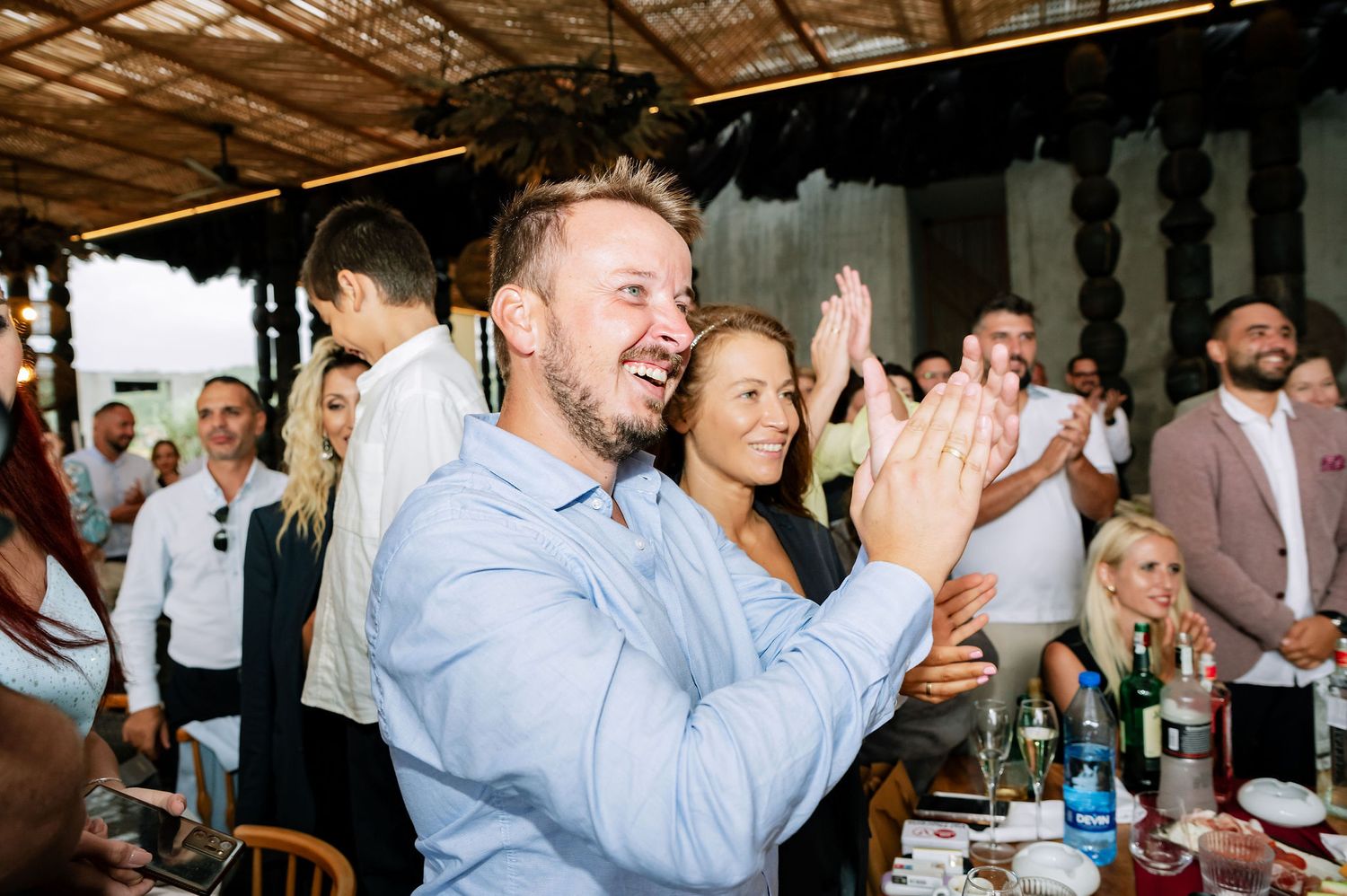Wedding guests applaud during celebration in modern industrial-style venue.