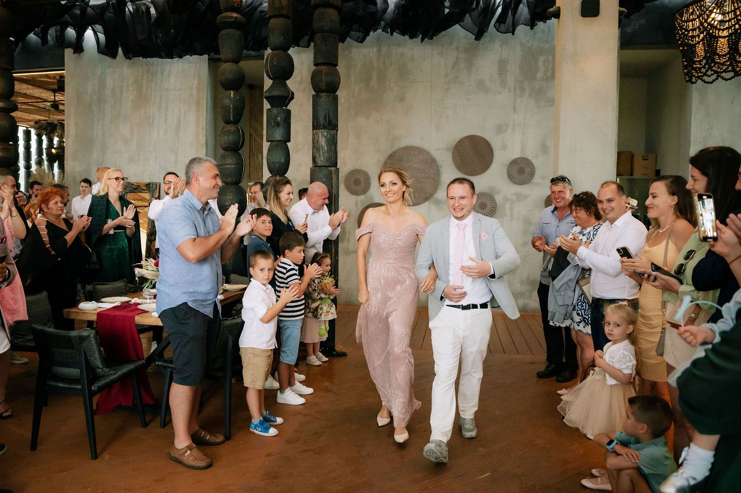 Wedding guests line the aisle clapping during a celebratory moment.