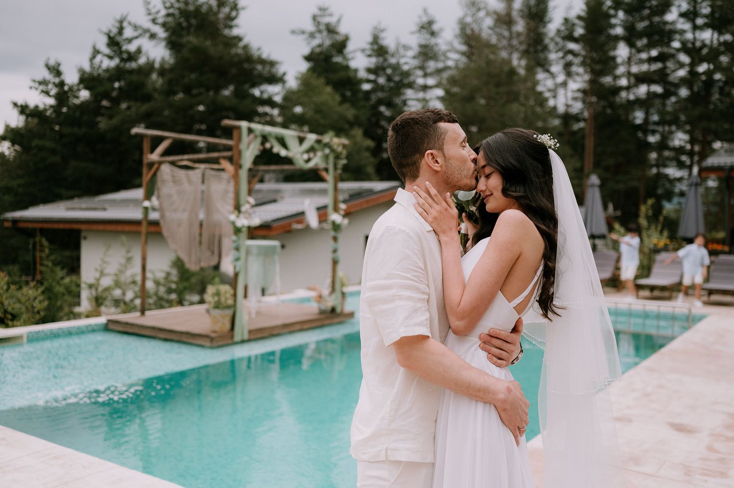 Romantic poolside wedding photos with a couple in matching white outfits.