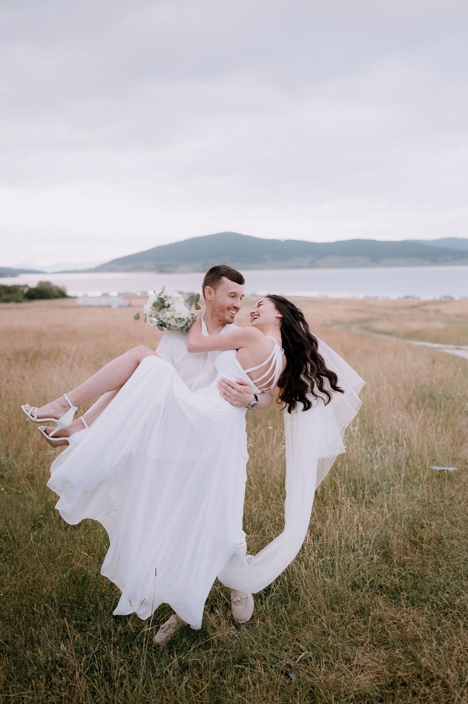 Elegant wedding dance lift photographed in a seaside meadow during golden hour.
