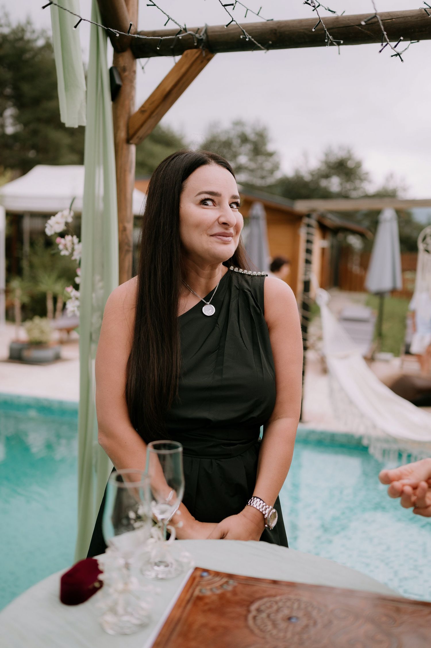Outdoor poolside wedding celebration with guests enjoying drinks and conversation.