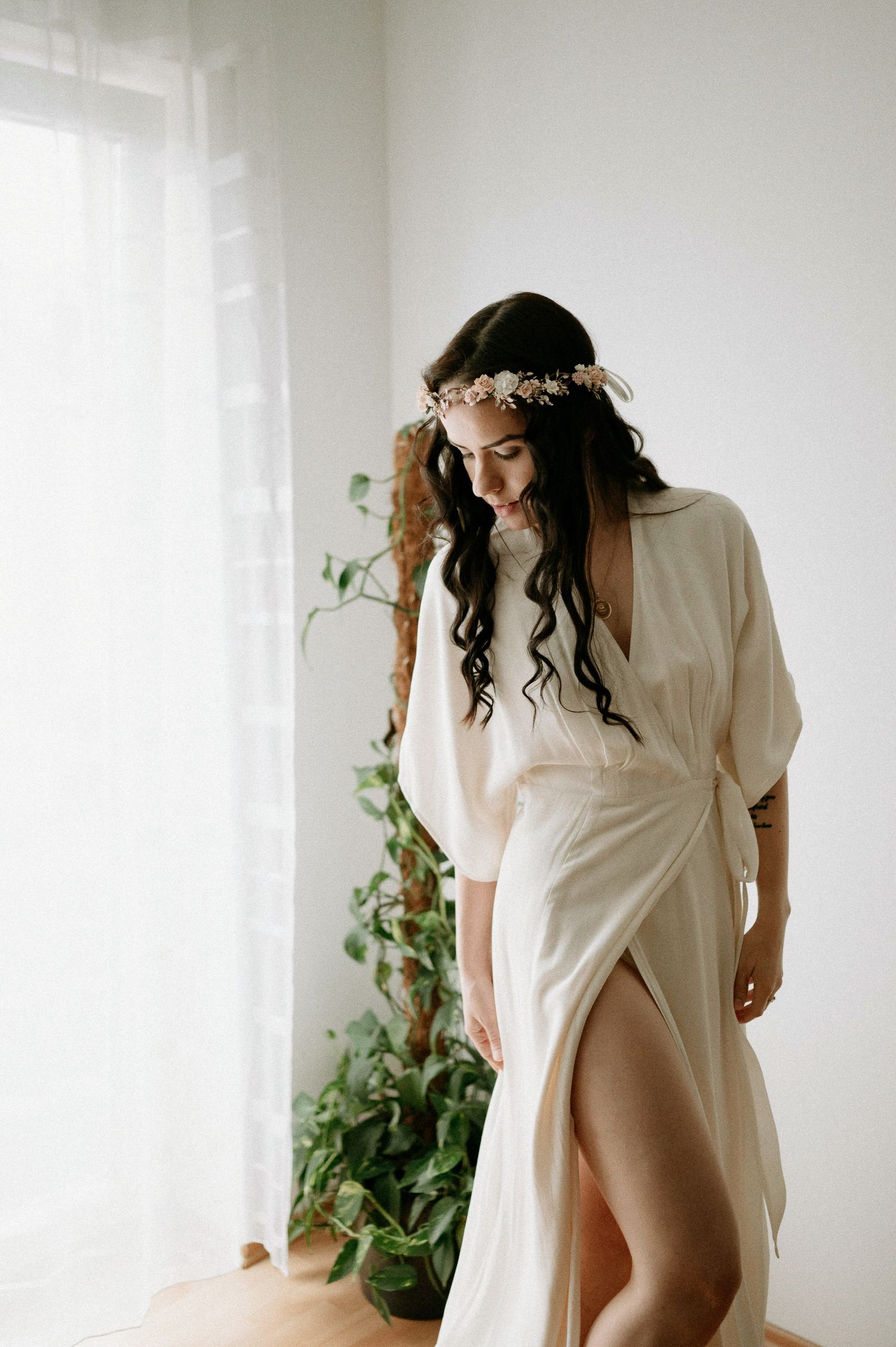 Intimate portrait with dramatic fabric movement against white walls and indoor plants.