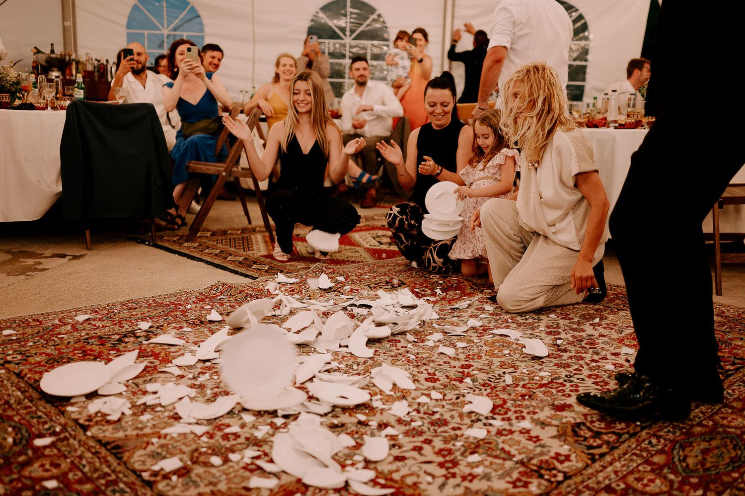 Wedding guests dance and celebrate on a confetti-covered dance floor at an indoor reception.