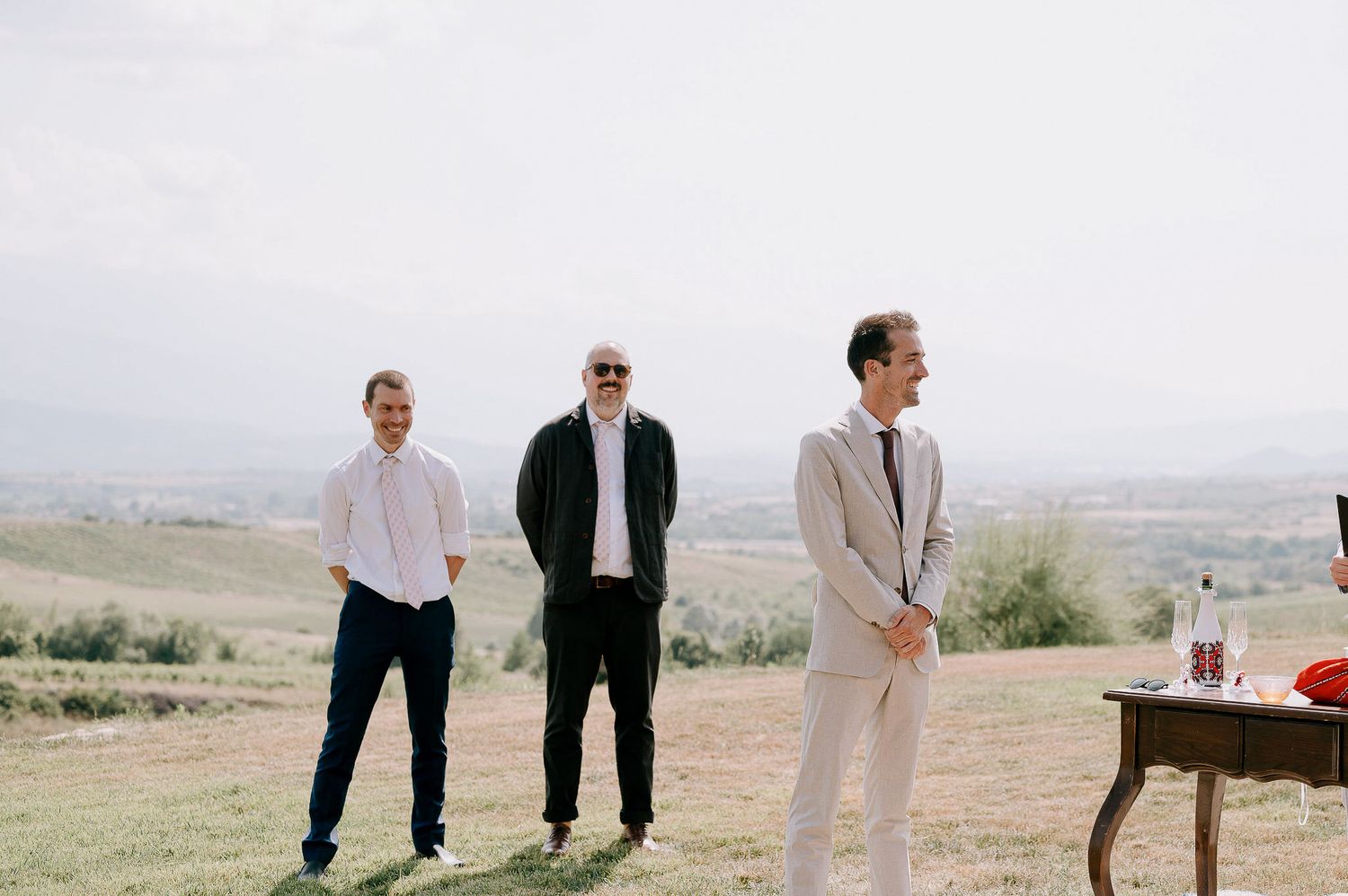 Wedding guests mingle on a scenic hilltop during an outdoor celebration.