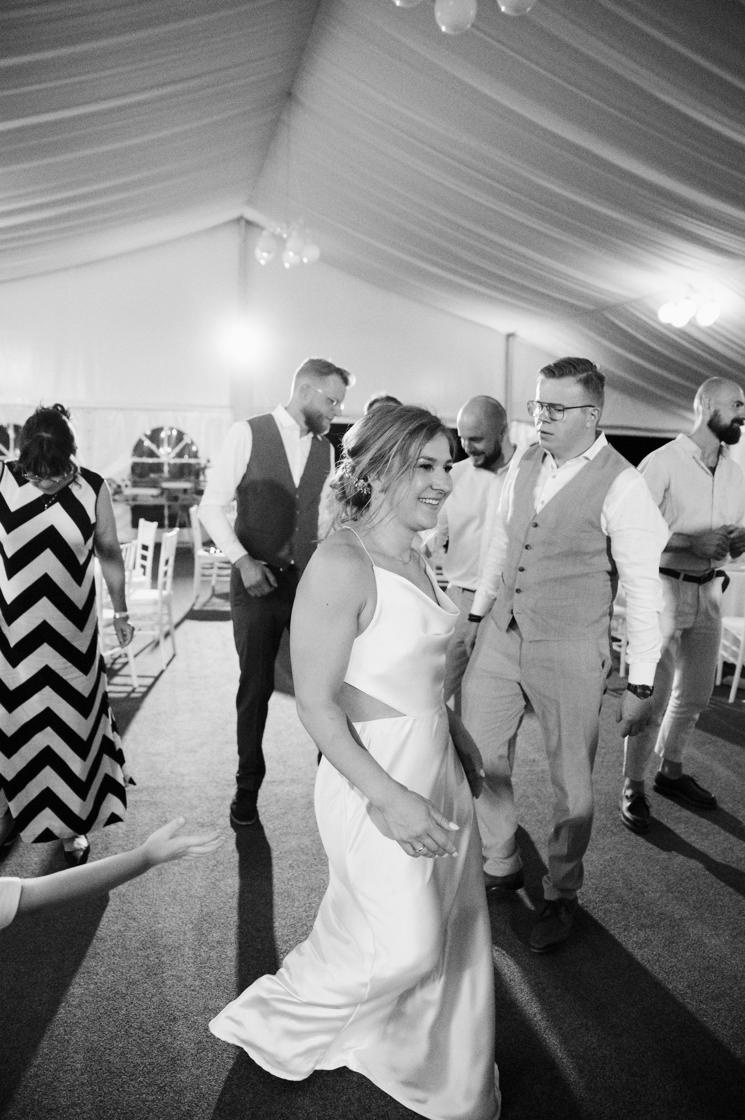 Black and white photos show couples dancing at a wedding reception under a white tent.