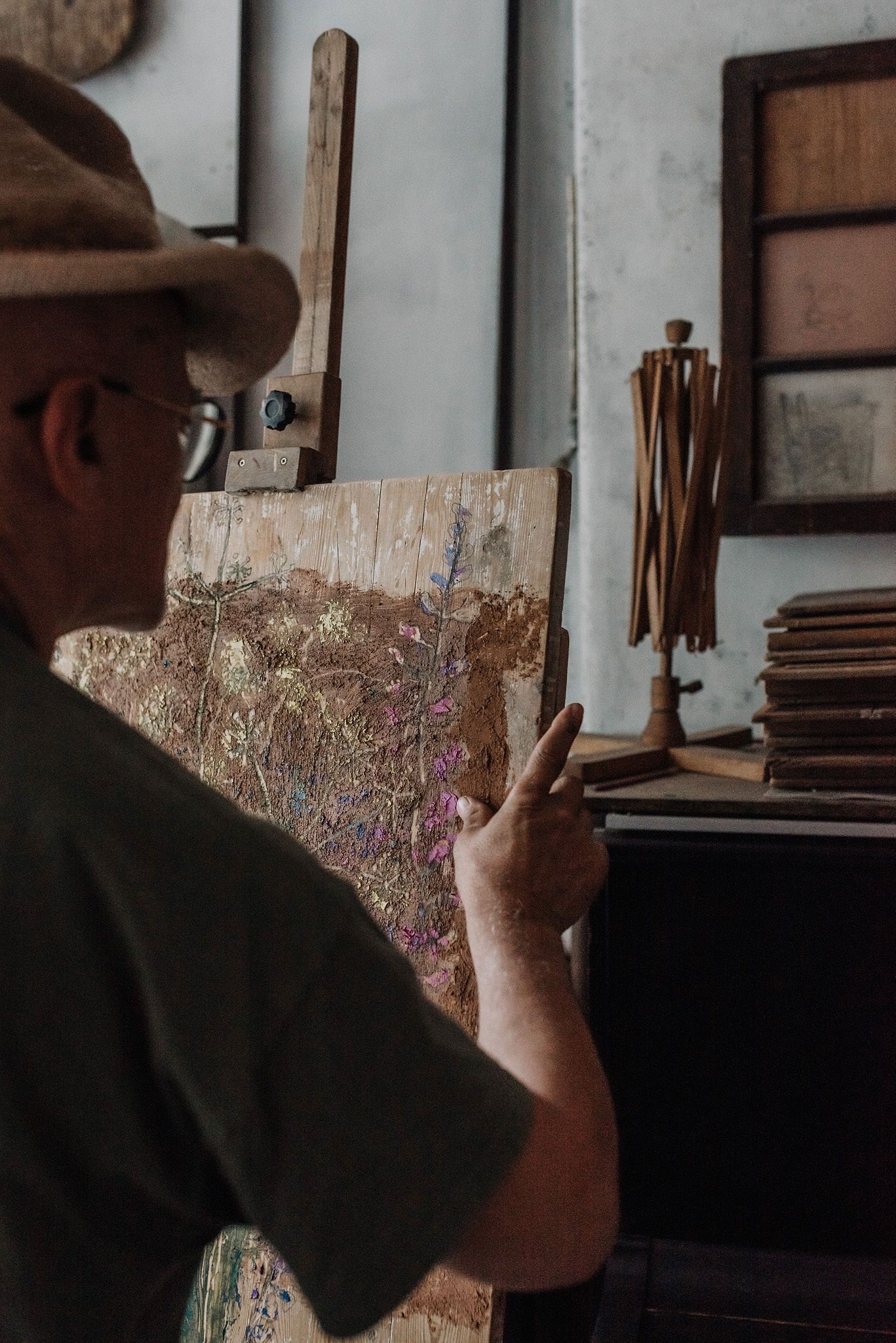 Hands hold a piece of weathered wood in an artistic workspace.