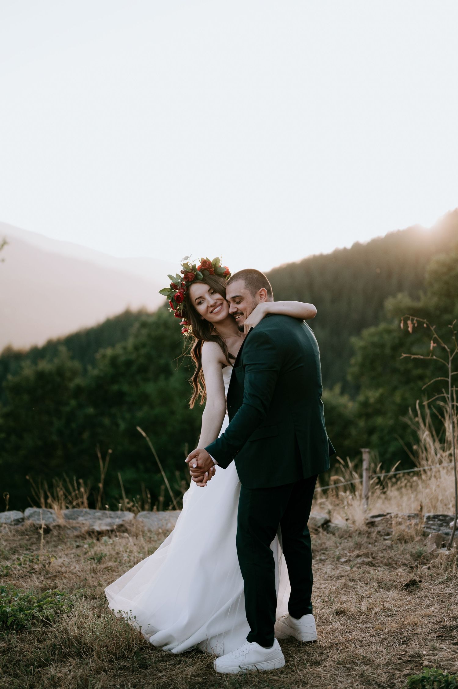 A tender wedding dance moment captured against golden mountain scenery.