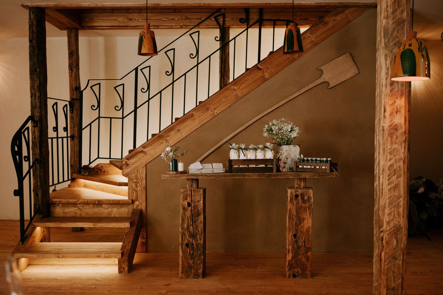 Interior view of a rustic venue with exposed wooden beams and staircase.