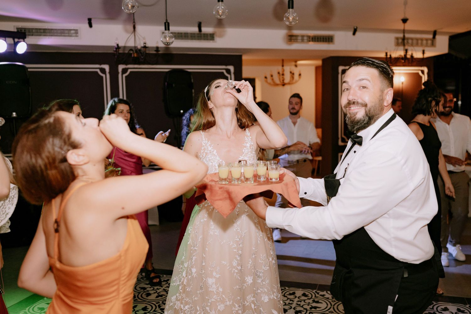 People dancing and celebrating together at an indoor party venue with pendant lighting and festive atmosphere.