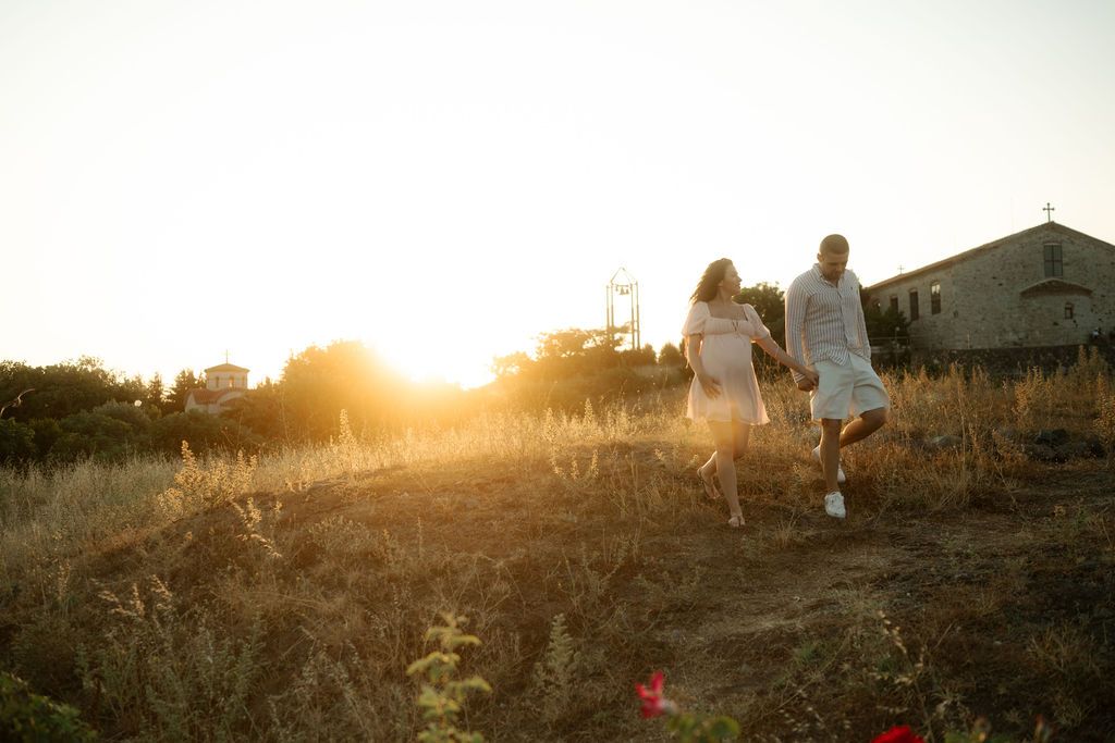 Silhouettes of people walking along a hillside path at golden sunset creating a dreamy atmospheric scene.