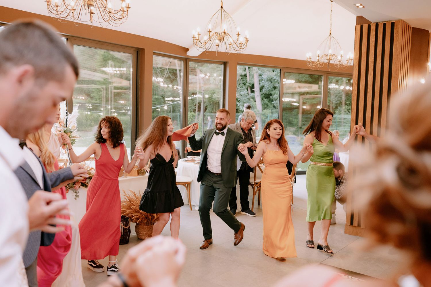 Wedding guests dancing together in a reception hall with warm lighting and elegant chandeliers.
