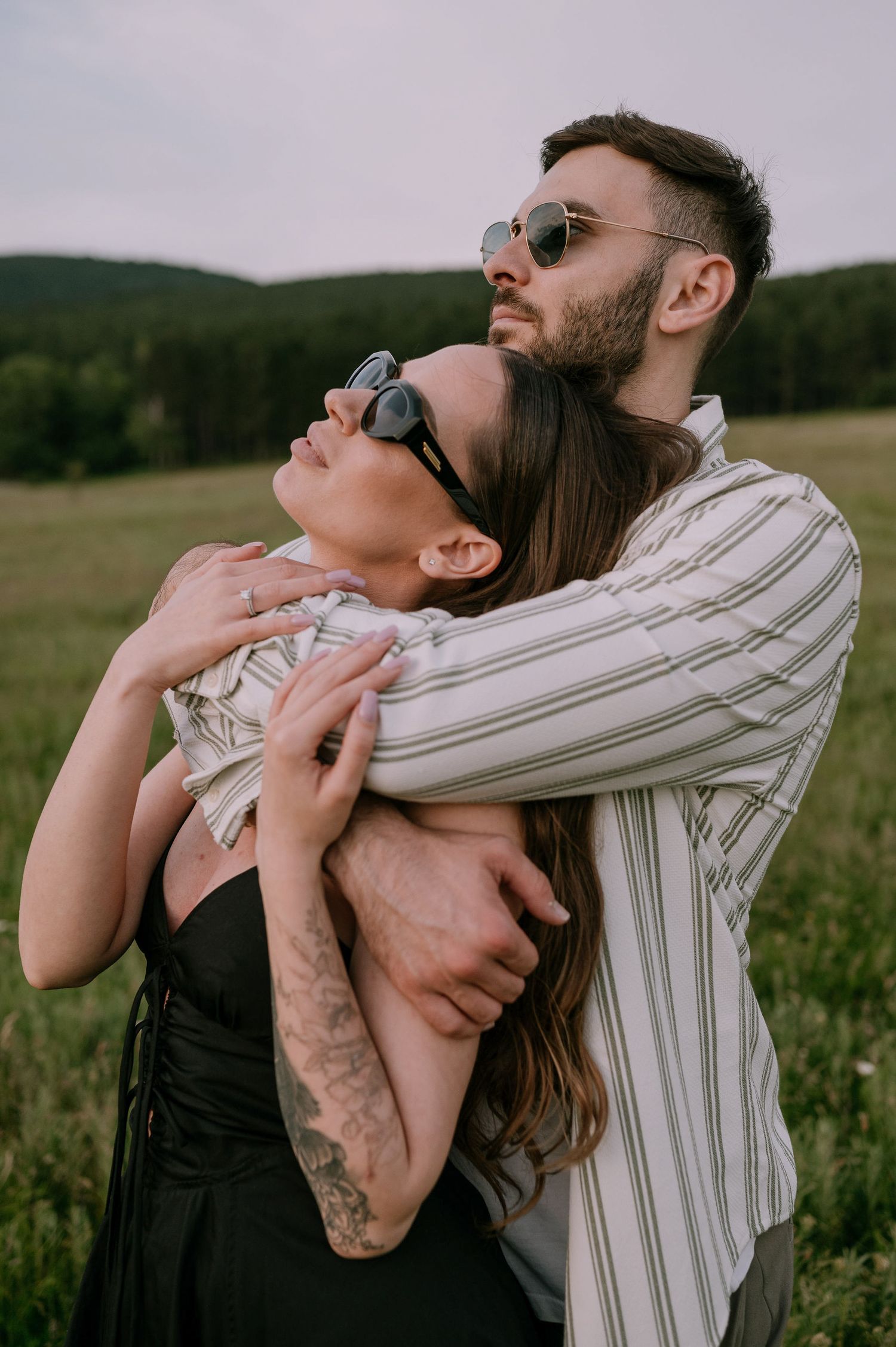 A couple embraces intimately in a grassy field wearing contrasting black and white outfits.