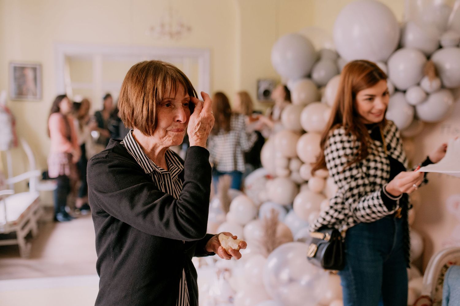 A couple embraces in front of a wall decorated with white balloons creating a romantic atmosphere.