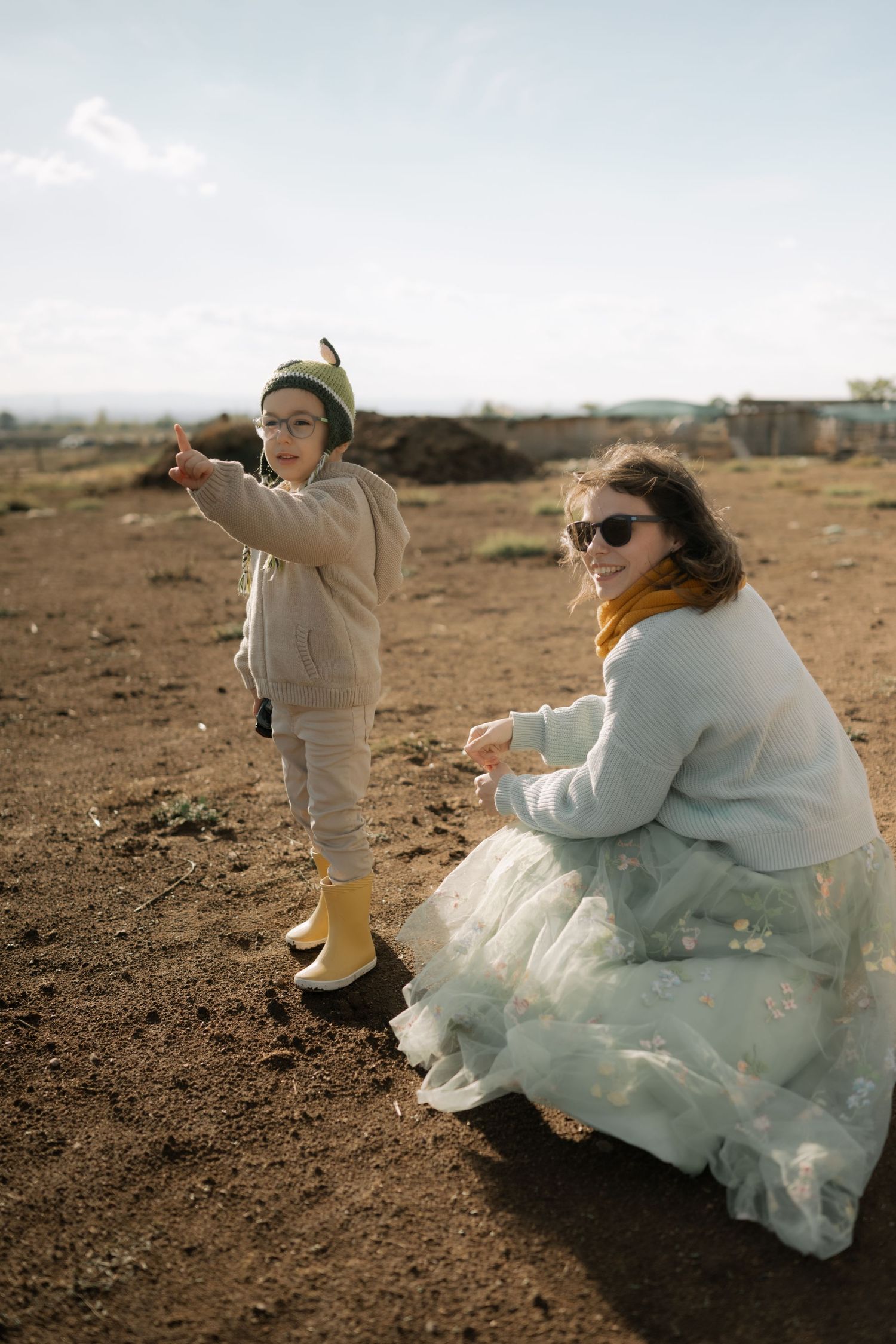 A couple dances playfully on a desert landscape with flowing white dress and beige outfit creating movement in the scene.