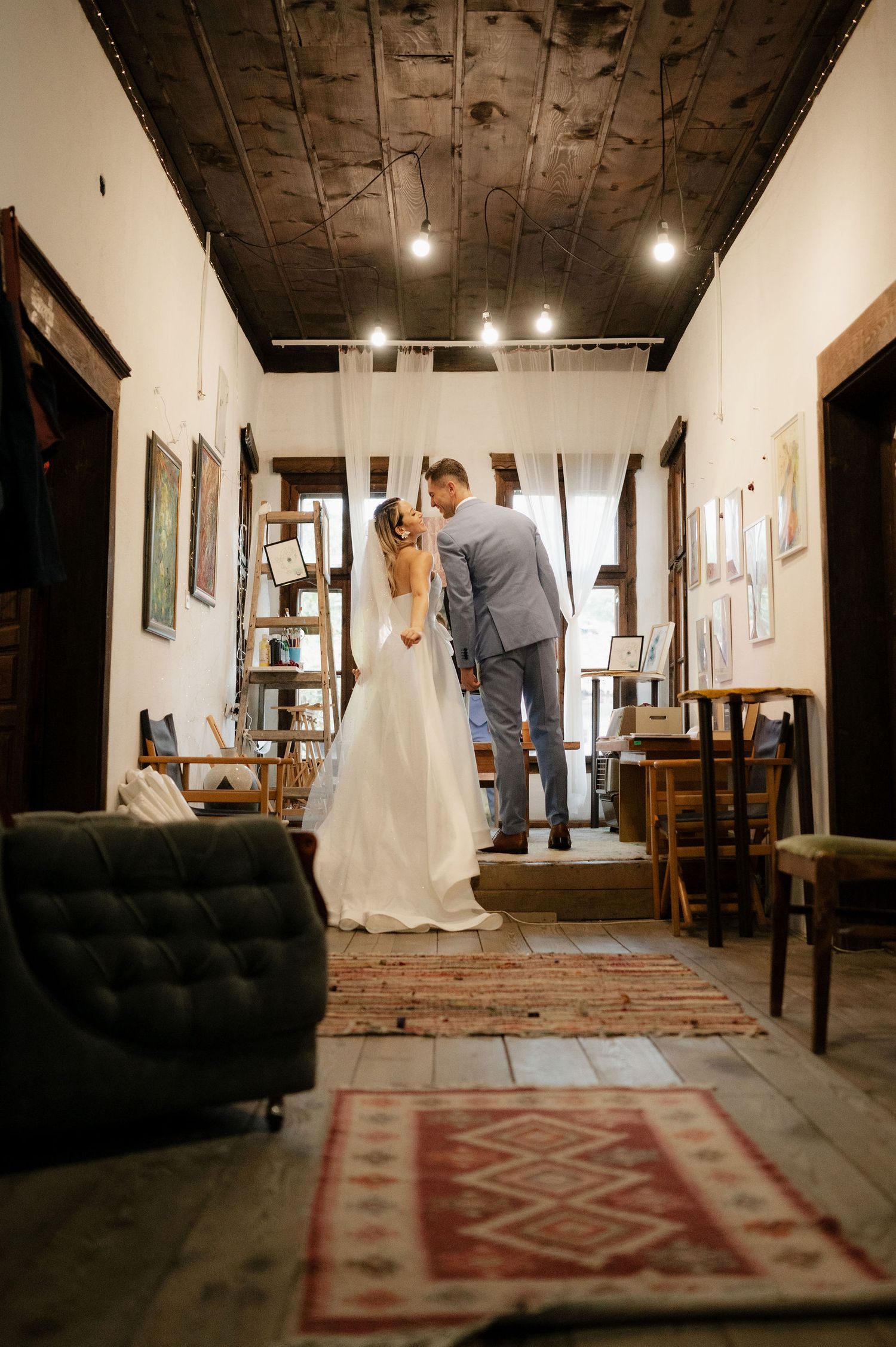 Interior of a rustic room with wooden floors, white walls, and a decorative red patterned rug.
