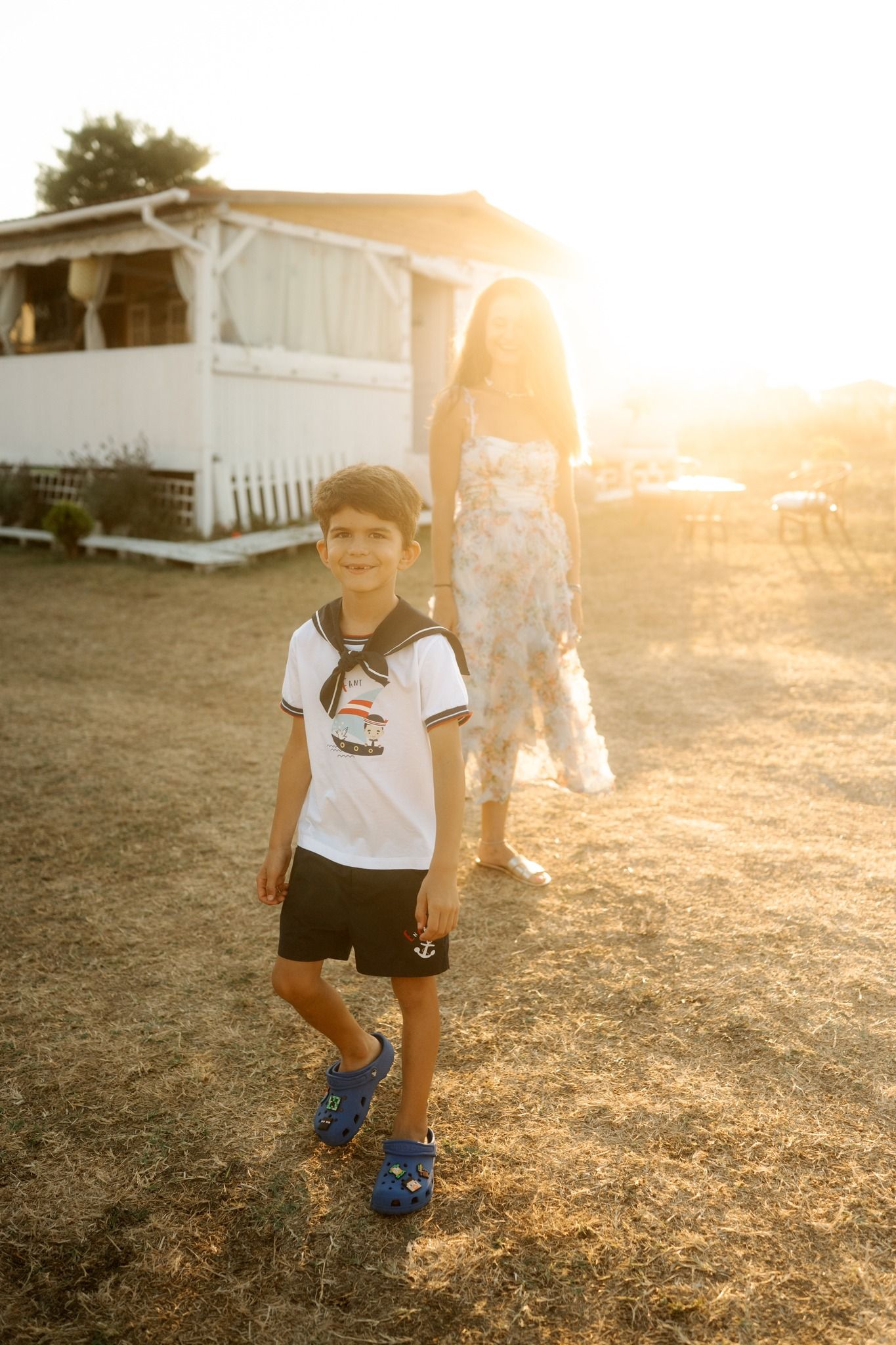 A young soccer player practices dribbling skills on a sunlit field during golden hour.