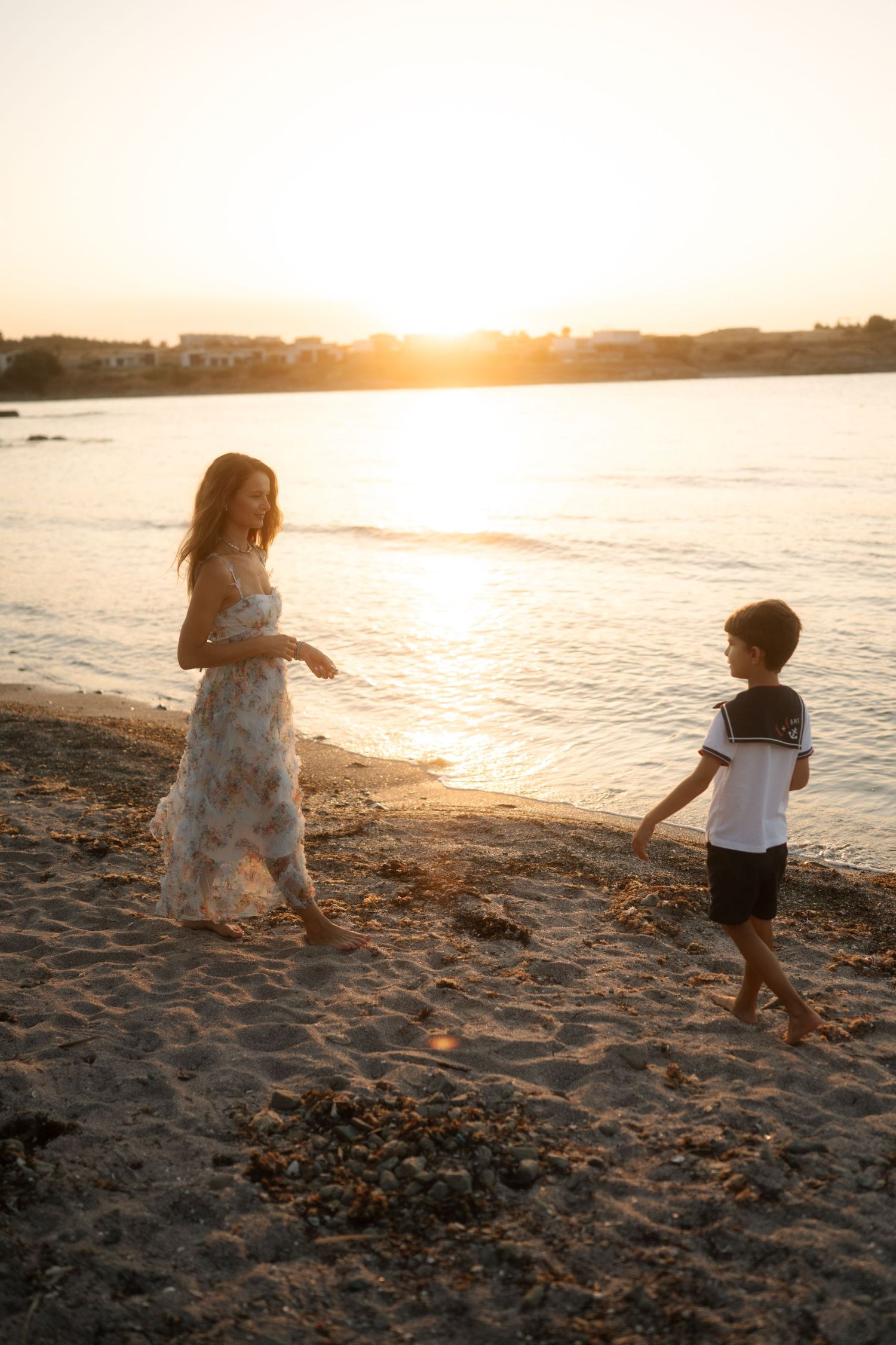 Two children playing on a sandy beach at sunset with golden light reflecting off the ocean waves.
