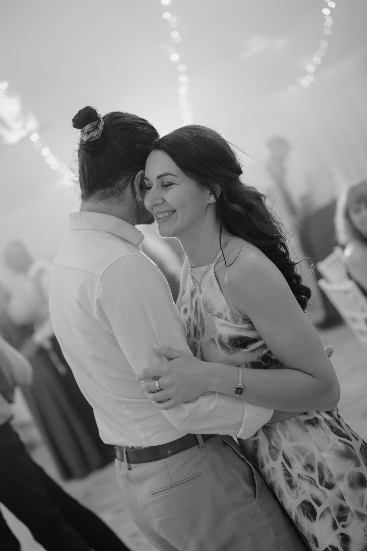 Black and white photo of a smiling couple sharing a romantic dance at a wedding reception.