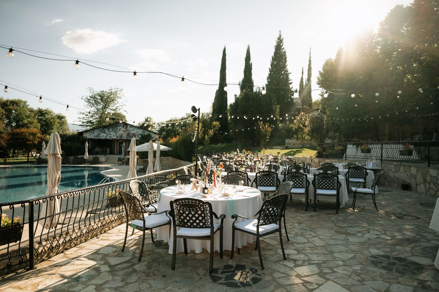 Outdoor wedding venue with string lights and rustic seating arrangements at sunset creates a romantic atmosphere.