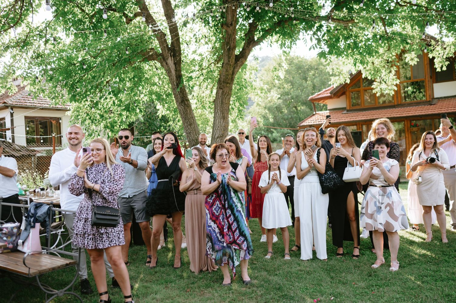 Wedding guests gathered outdoors in white attire celebrating at a garden ceremony.