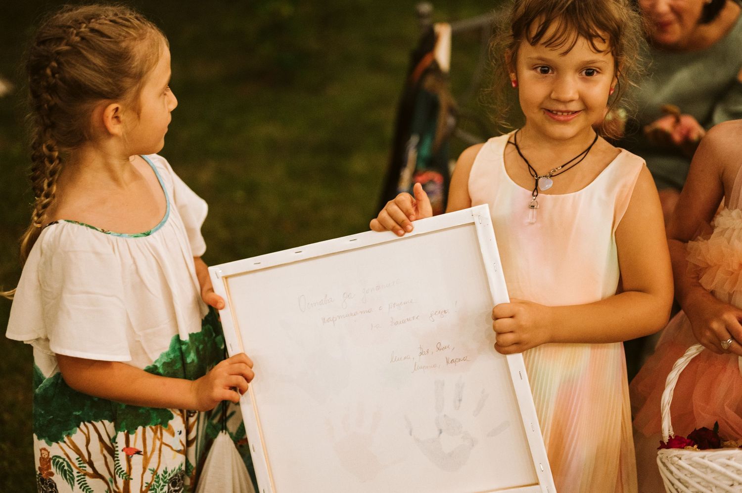 Children display colorful artwork at an outdoor event.