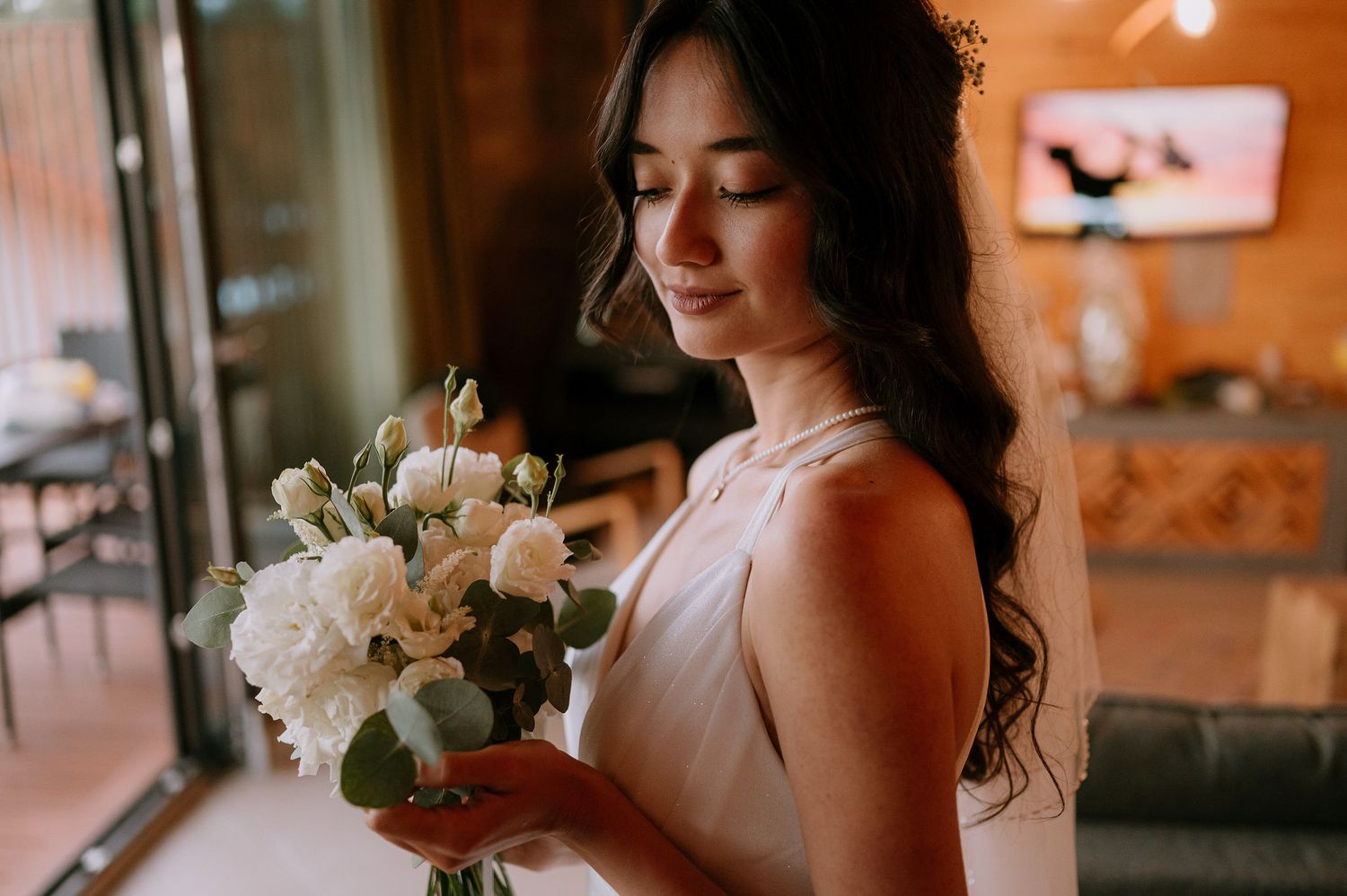 Candid moments of bride holding white floral bouquet in natural window light.
