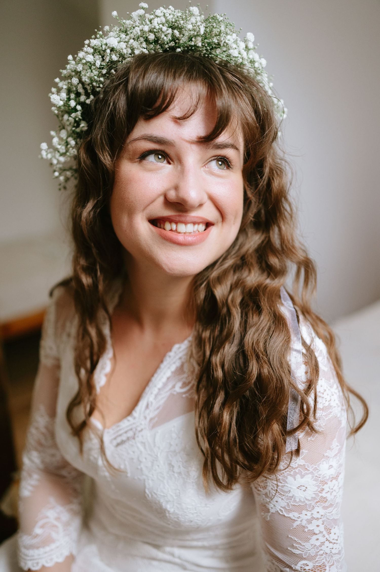 Candid bridal portraits showing a lace wedding dress and baby's breath crown in soft natural lighting.