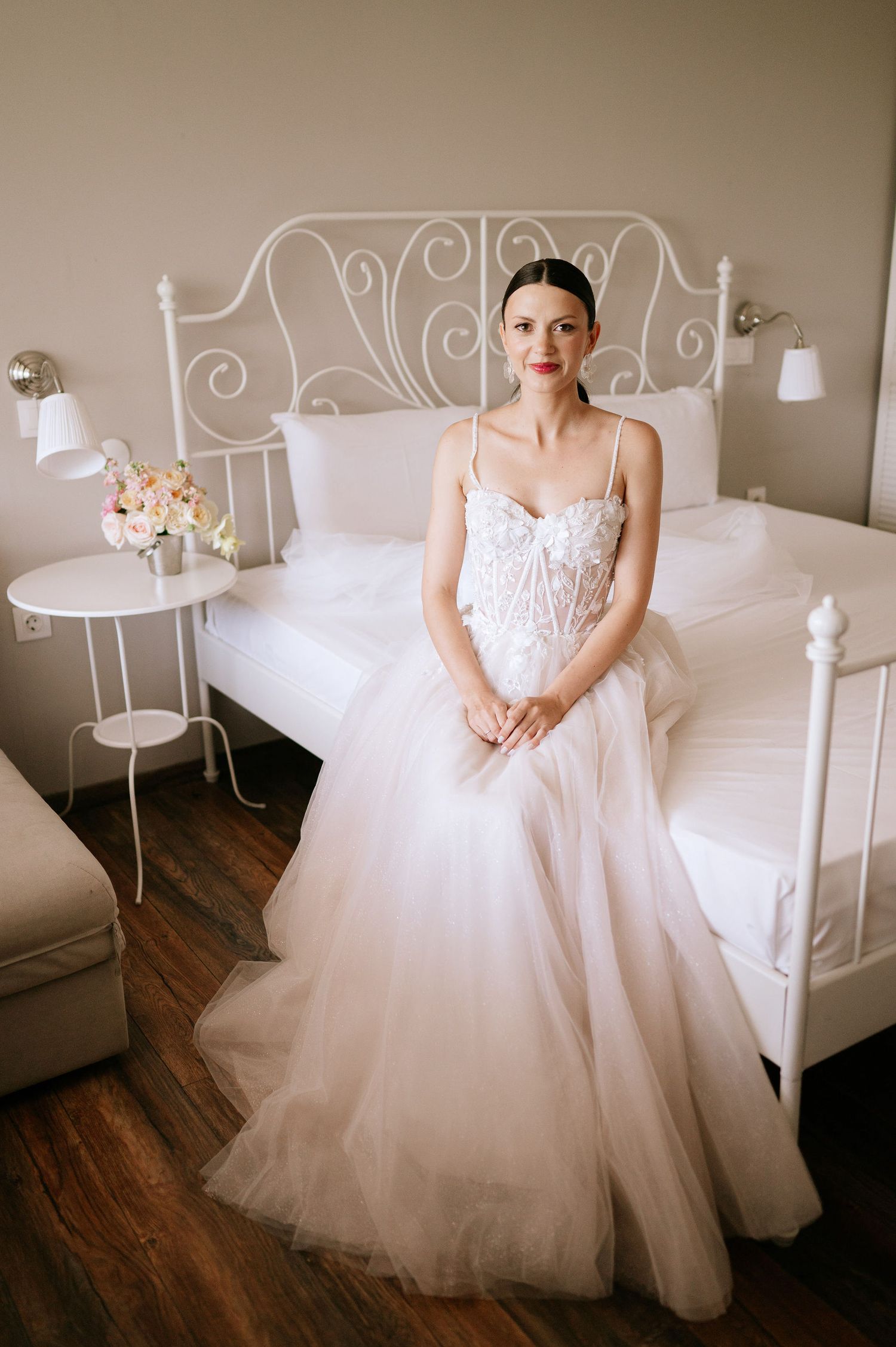 Ethereal wedding gown with delicate lace bodice and full tulle skirt in soft bedroom setting.