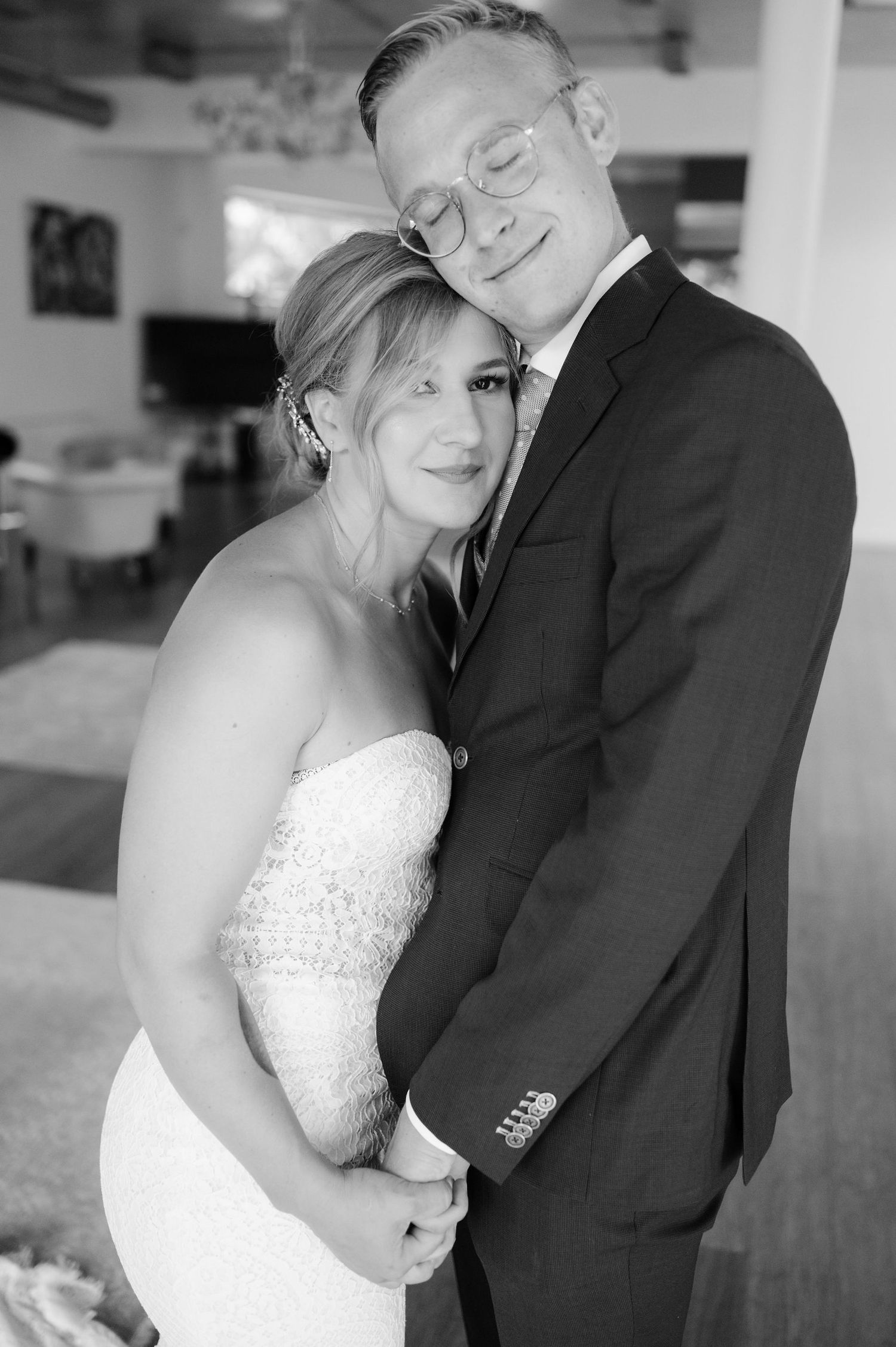 A black and white portrait captures a gentle embrace between newlyweds.