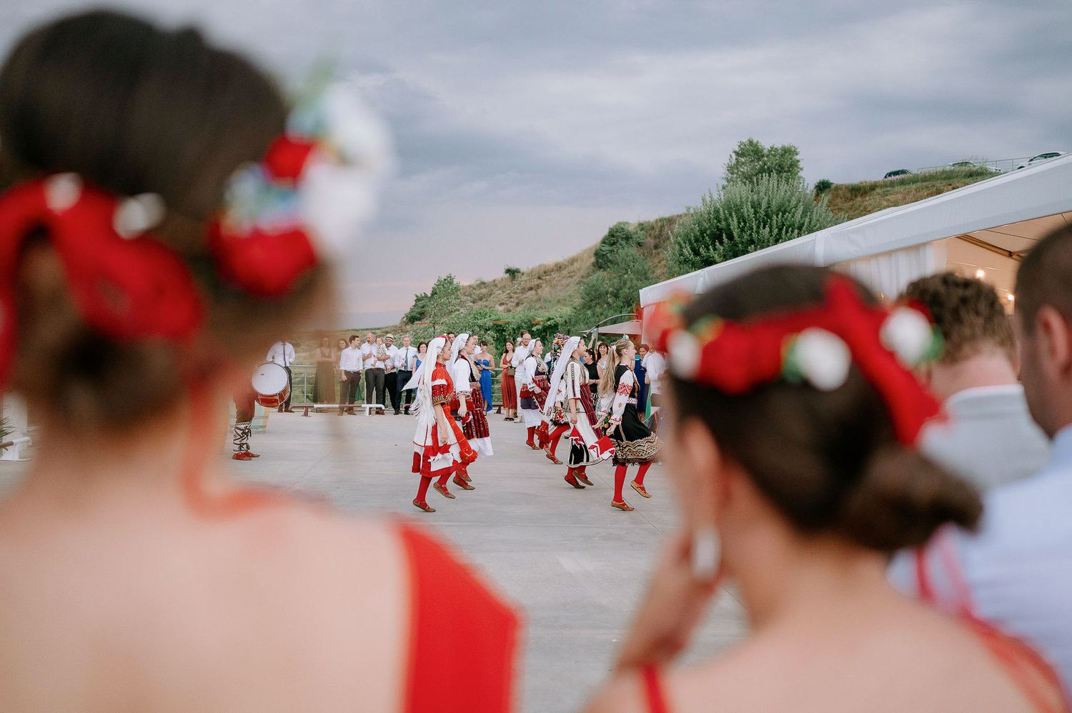 Traditional folk dancers in red and white costumes perform at an outdoor celebration.