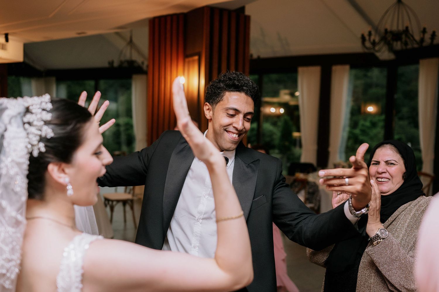 Wedding party dancing and celebrating in an indoor venue with warm lighting and decorative elements.