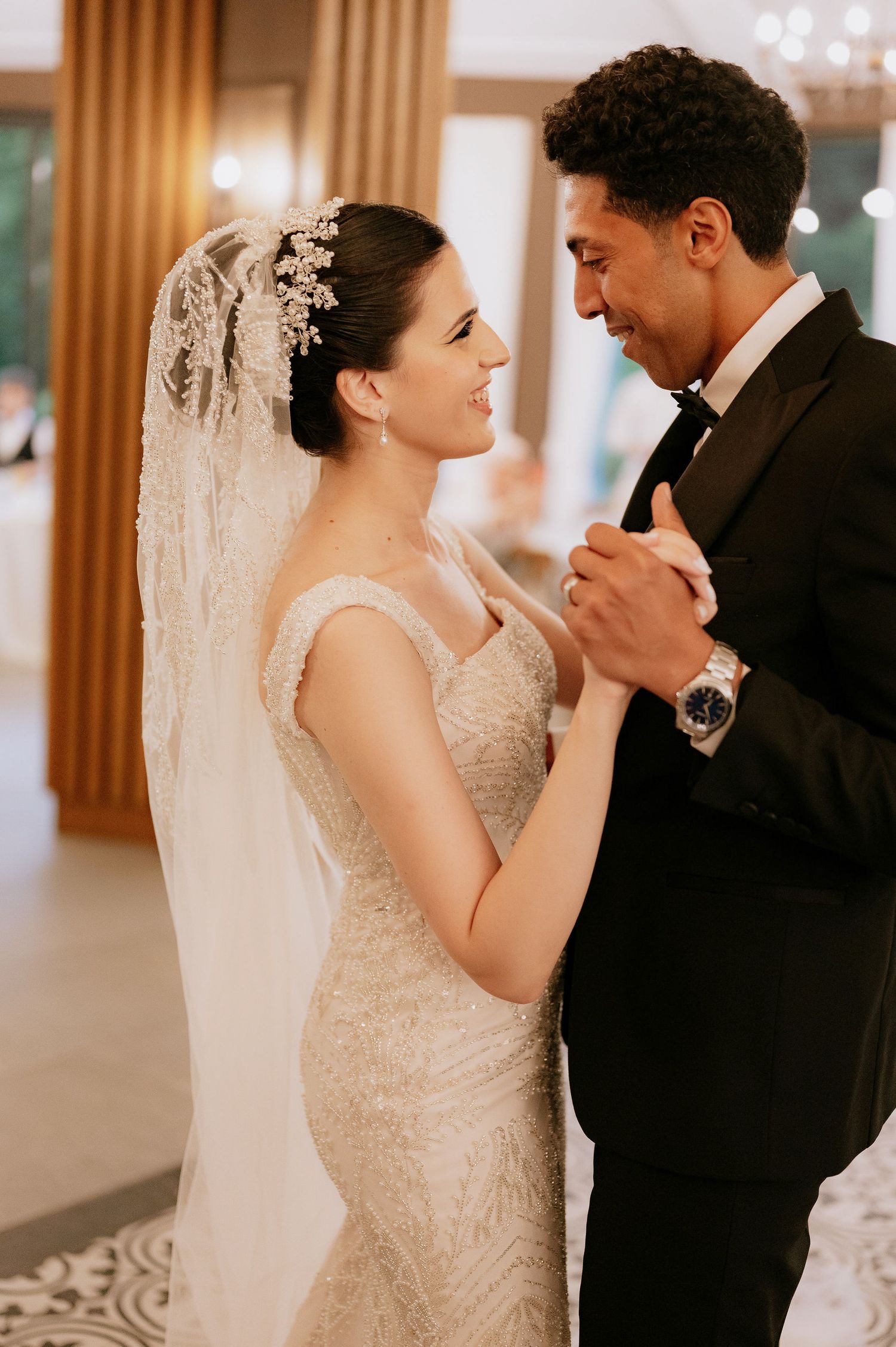 A romantic first dance moment in an elegant reception venue with patterned floors and warm lighting.
