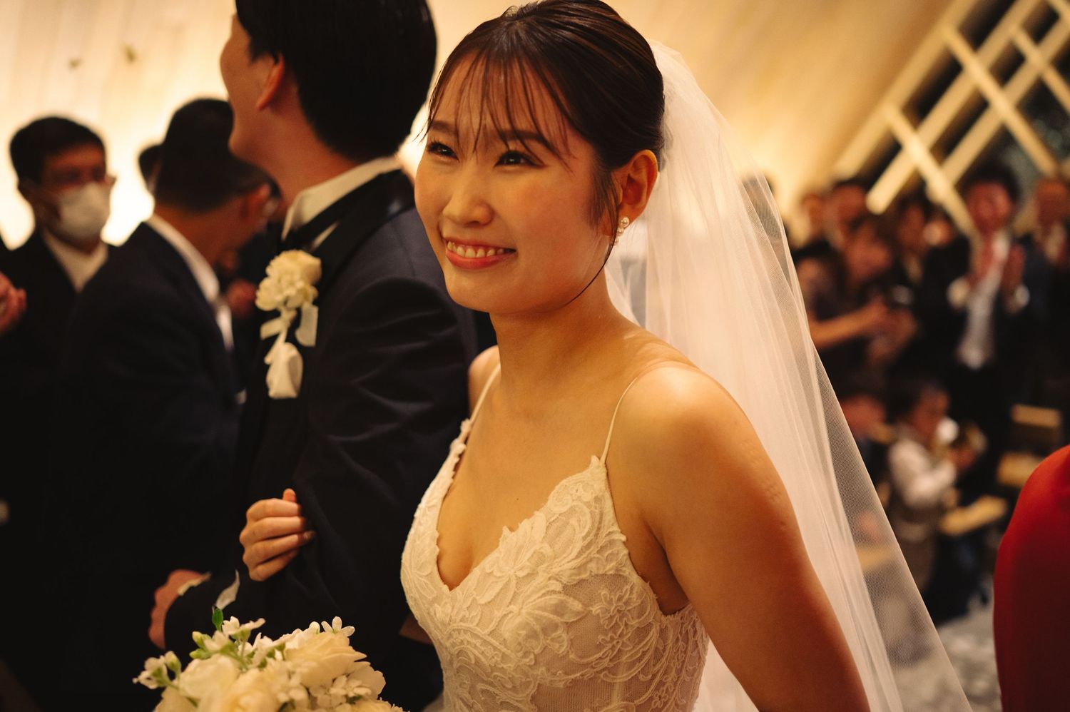 A radiant bride in a white lace dress and veil during wedding reception celebrations.