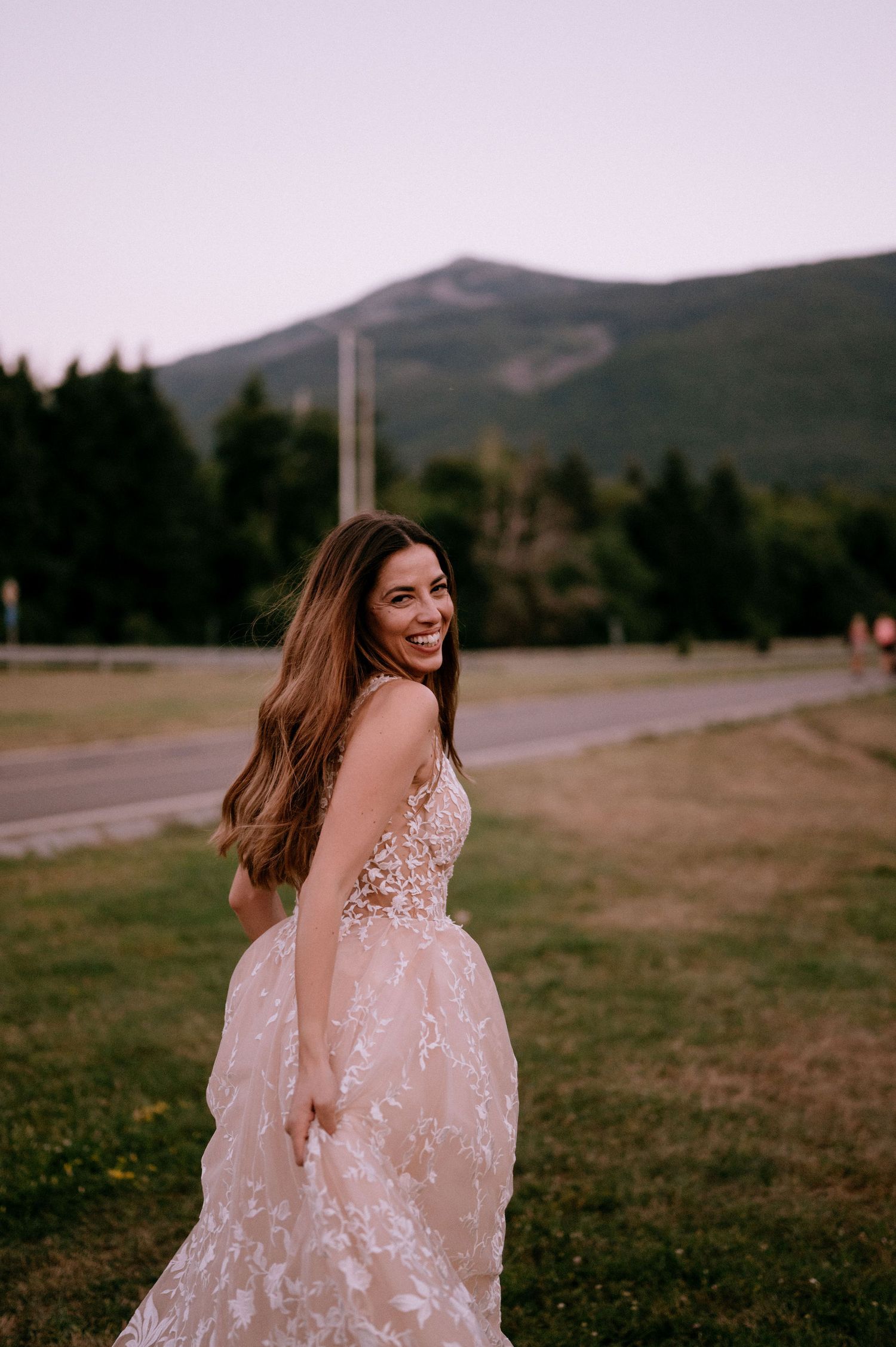 Joyful moment captured in blush wedding dress against mountain backdrop.