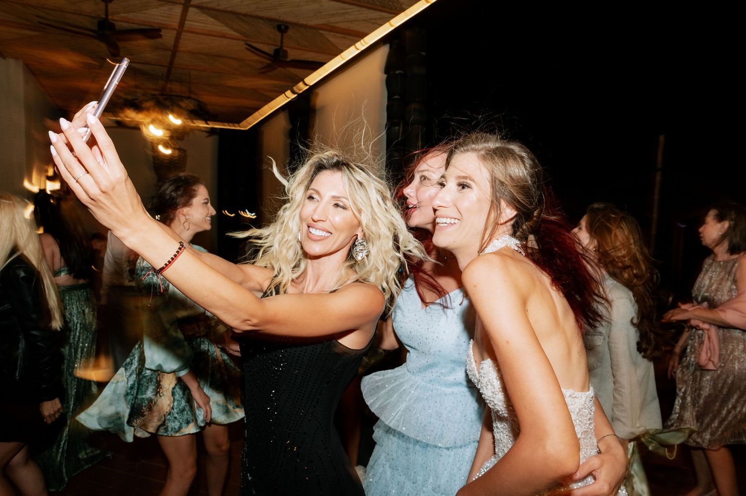 Party guests dancing and celebrating with joyful expressions in an indoor venue.