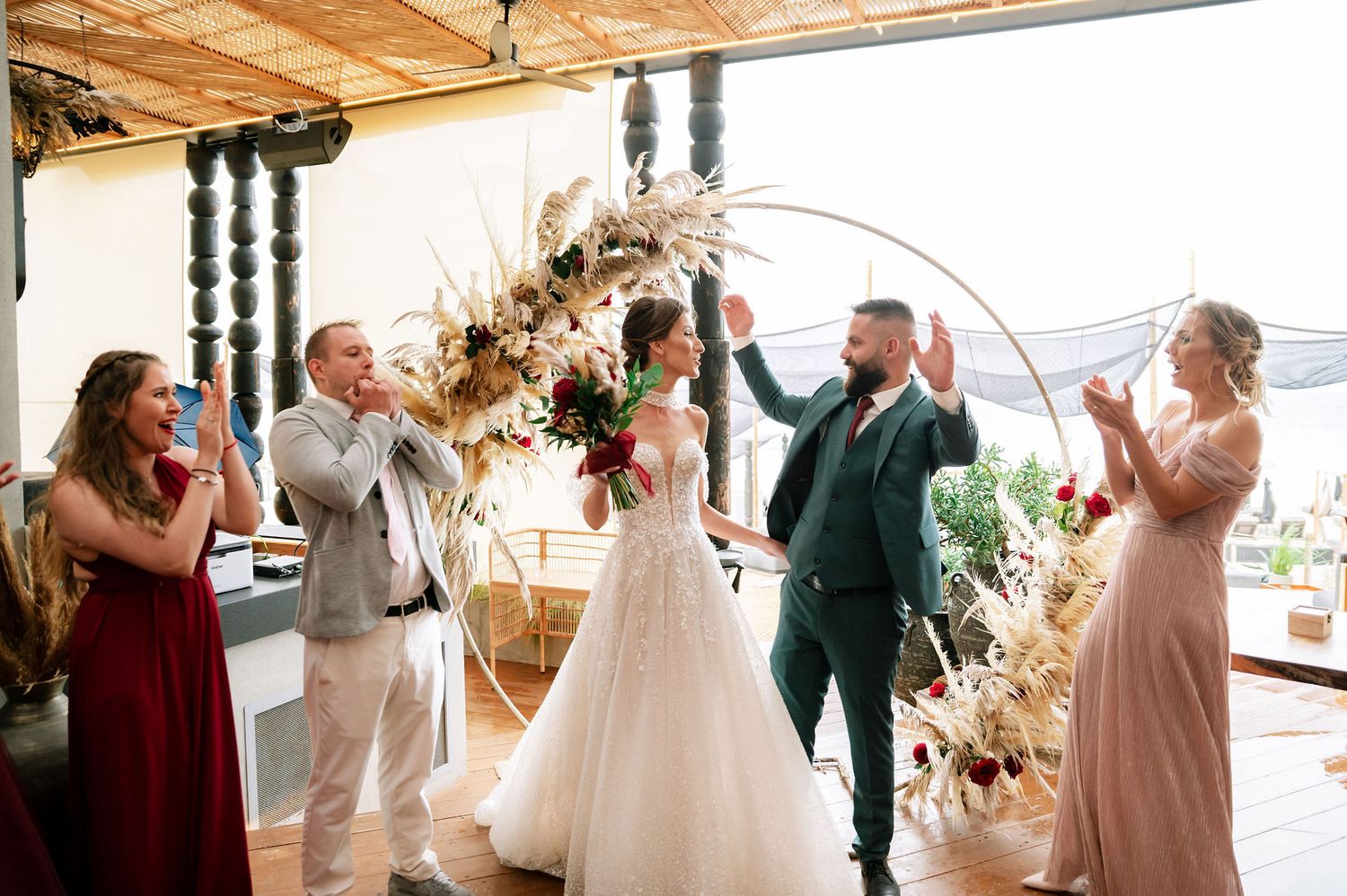 Joyful wedding scene in a wooden-beamed venue with elegant dried floral arrangements.