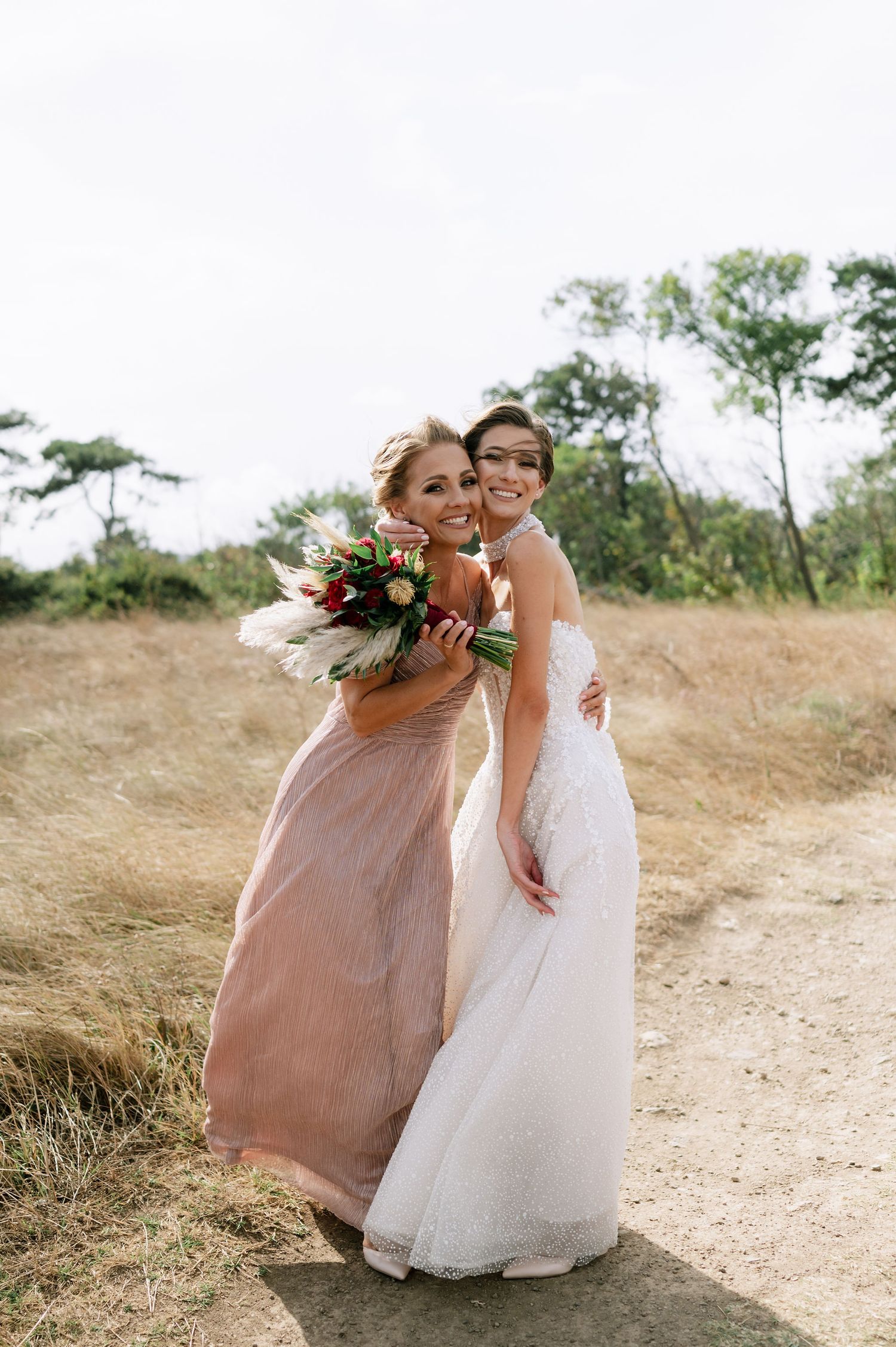 Two people in formal attire share an intimate moment on a scenic outdoor path.